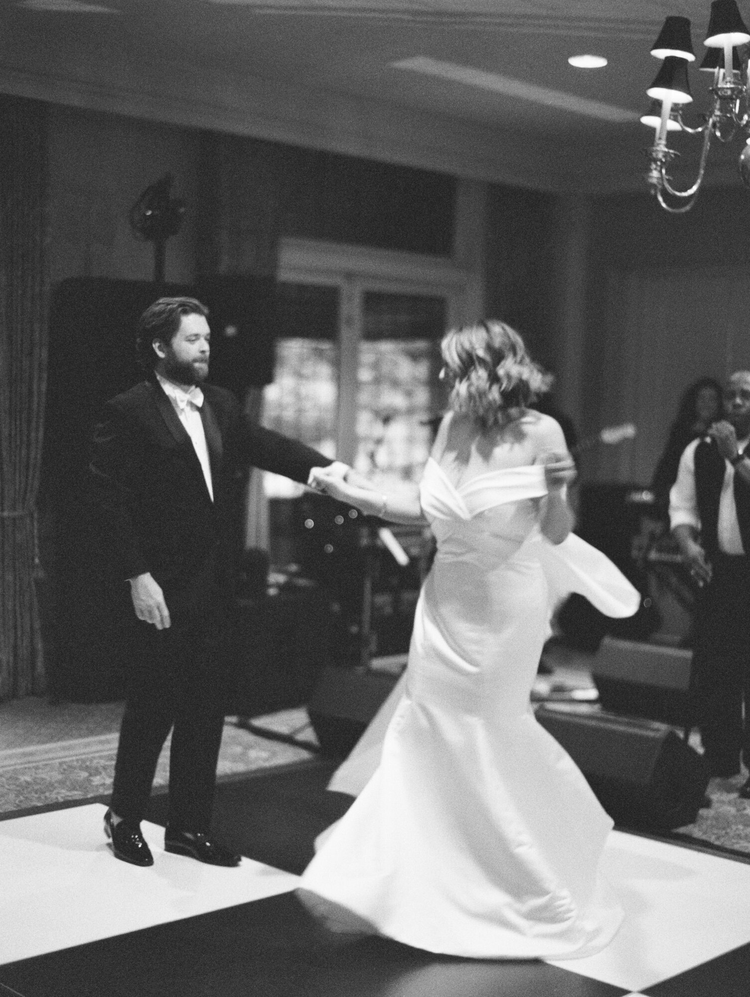 bride dances with groom on checkerboard dance floor black and white
