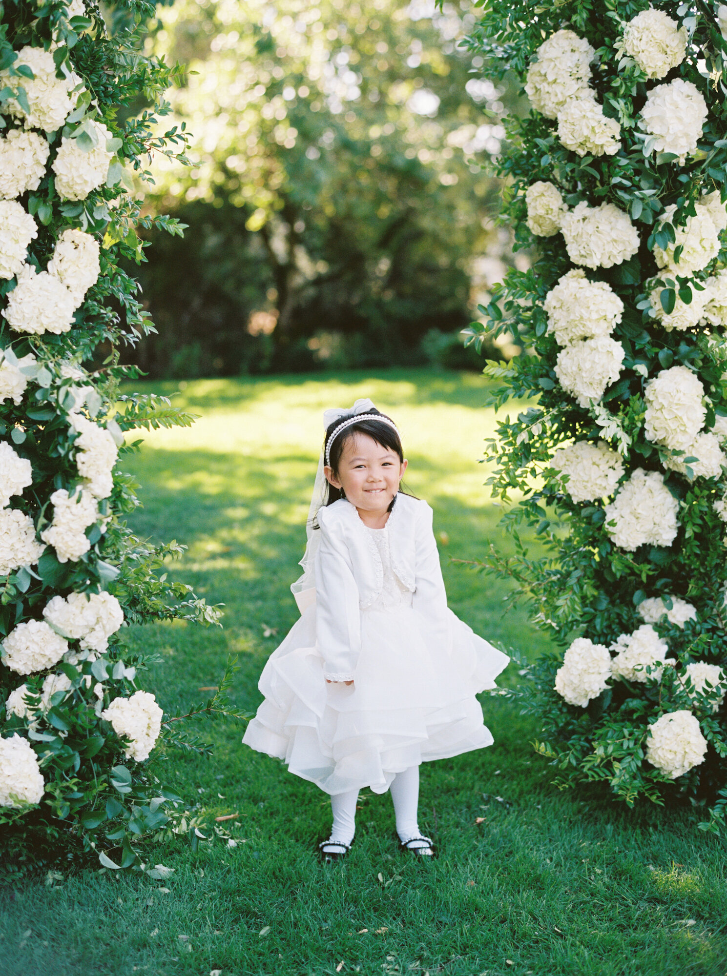 white hydrangea wedding arch  with flower girl