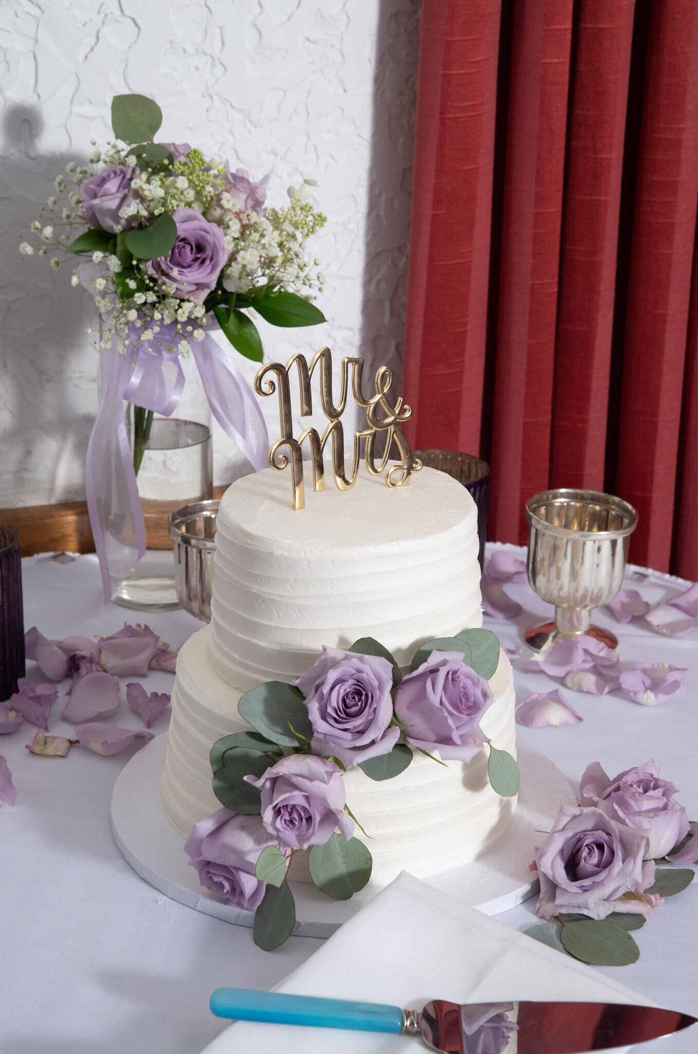 two tier white wedding cake with purple roses