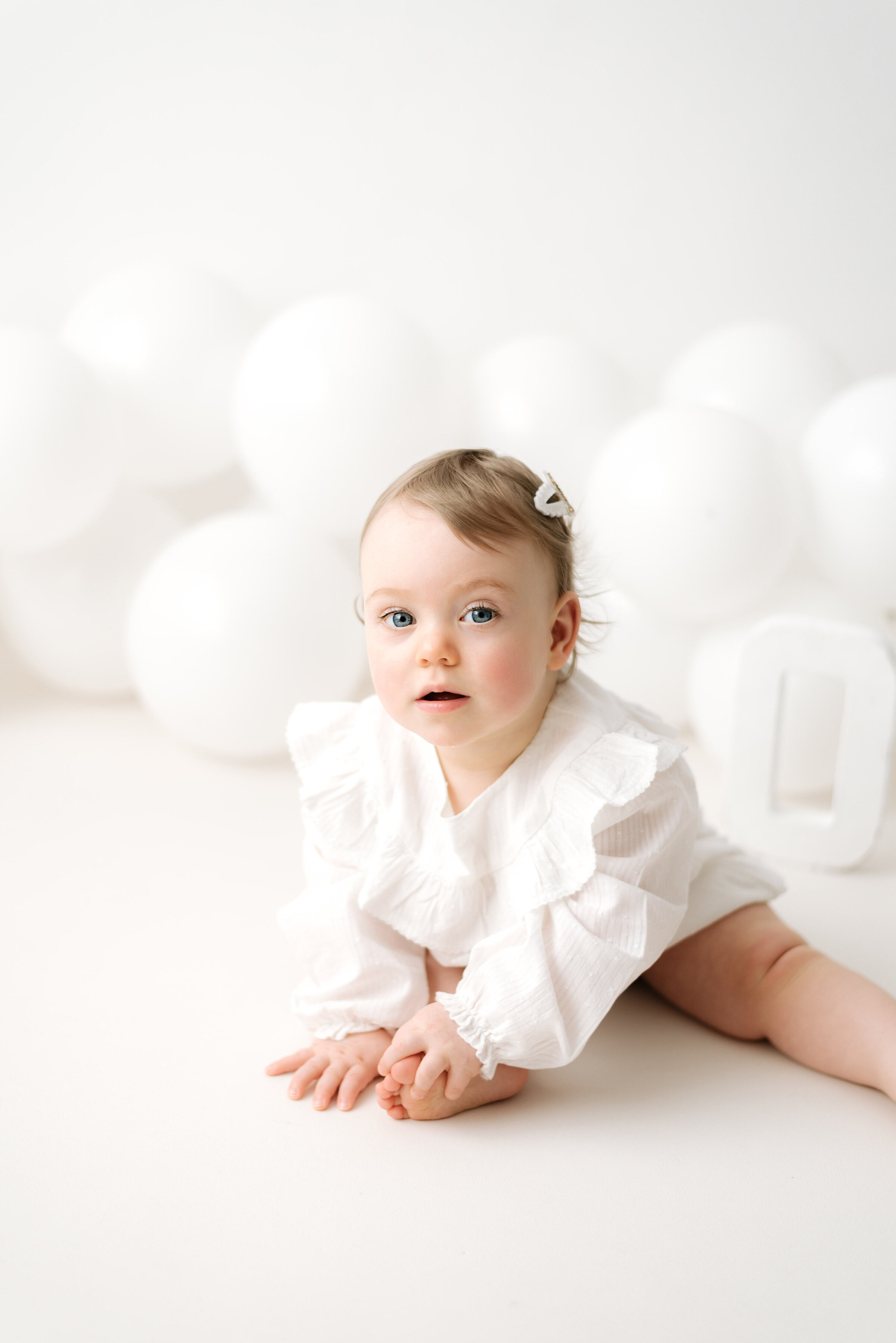 Little girl sitting on a white floor at billingsurst cake smash photoshoot