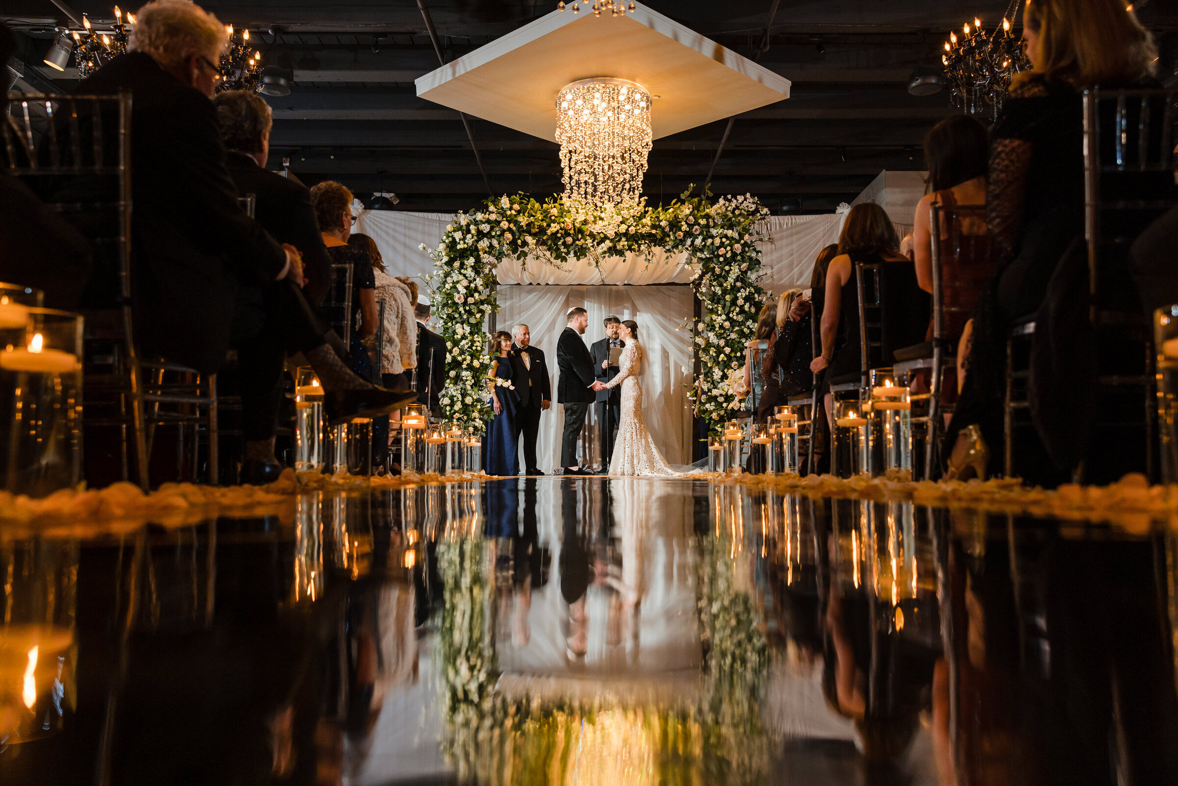 Wide angle view of the Jewish wedding ceremony at Tendenza reflected on the glass aisle runner