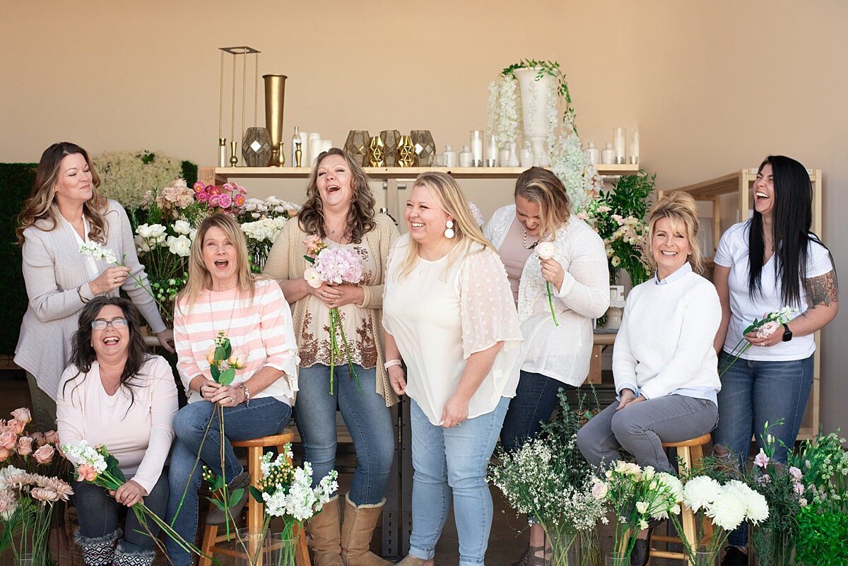 Team Photo inside the flower studio for Larson Floral Co. Girls gathered together laughing and putting together flower arrangements
