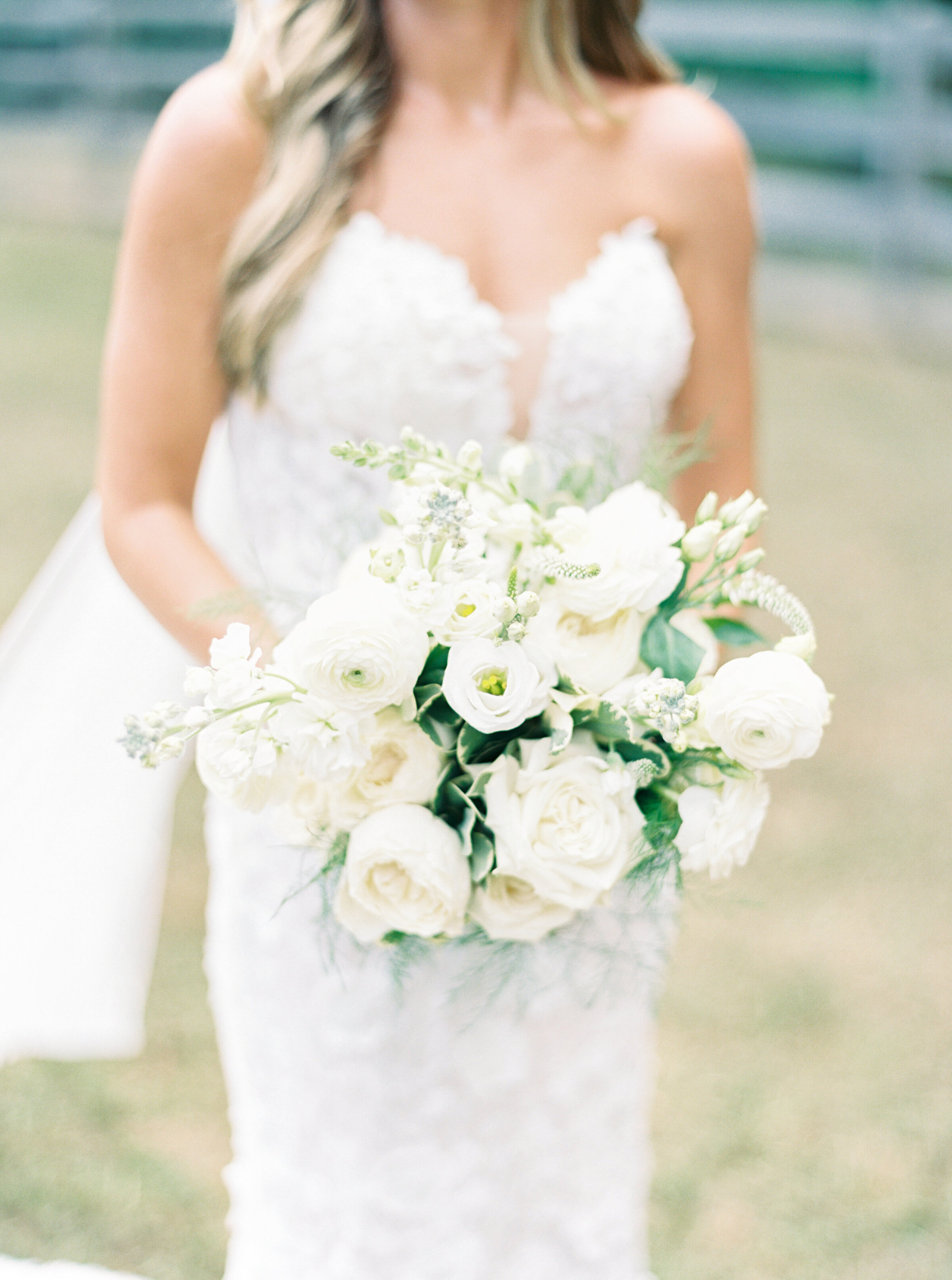 Bride in a lace dress holding bouquet of white roses