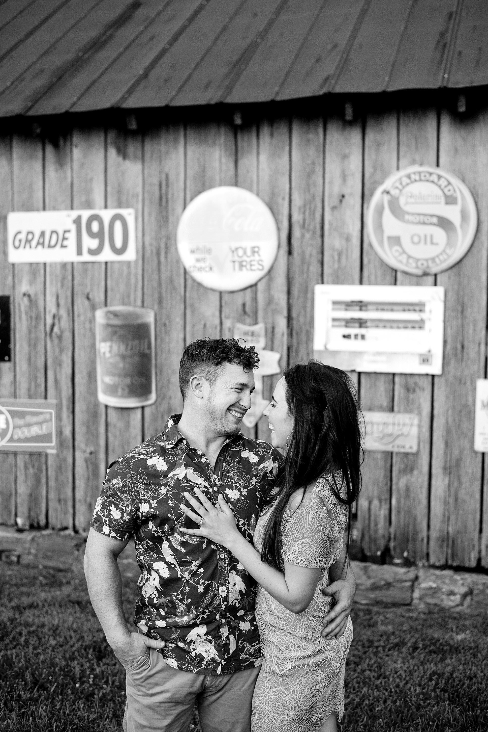 Black and White photo of couple laughing candidly in front of vintage signs