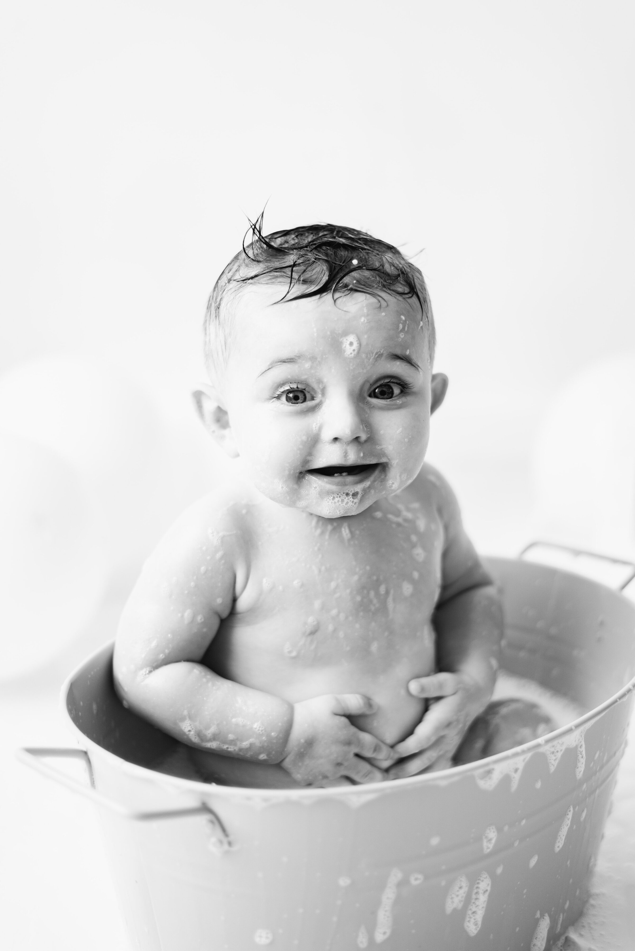 Little boy in a bubble bath covered in bubbles in billingshurst cake smash photoshoot