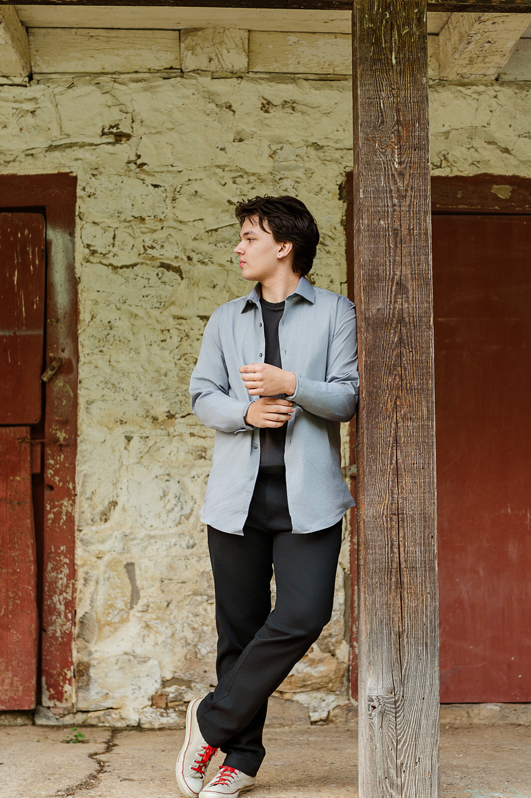 Senior boy standing confidently by a rustic barn door in York, PA