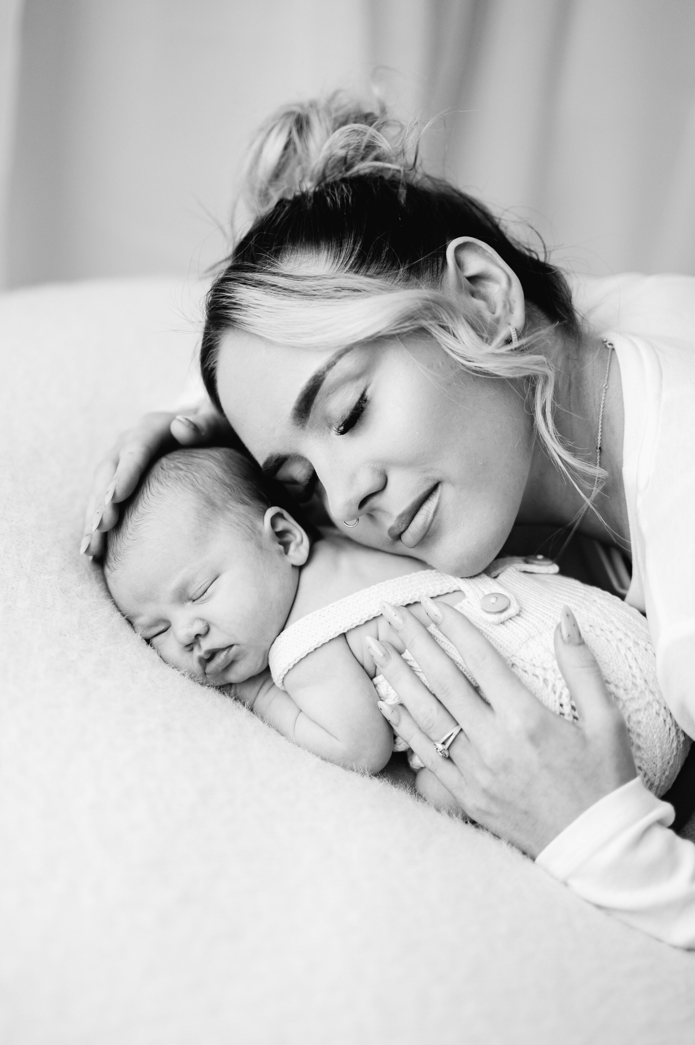 A new mum at a Billingshurst newborn photoshoot leaning over her newborn daughter and cuddling her