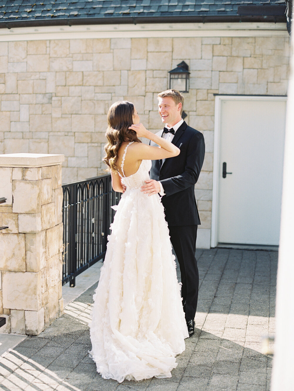 groom in black tux smiling at bride with hair down and wavy