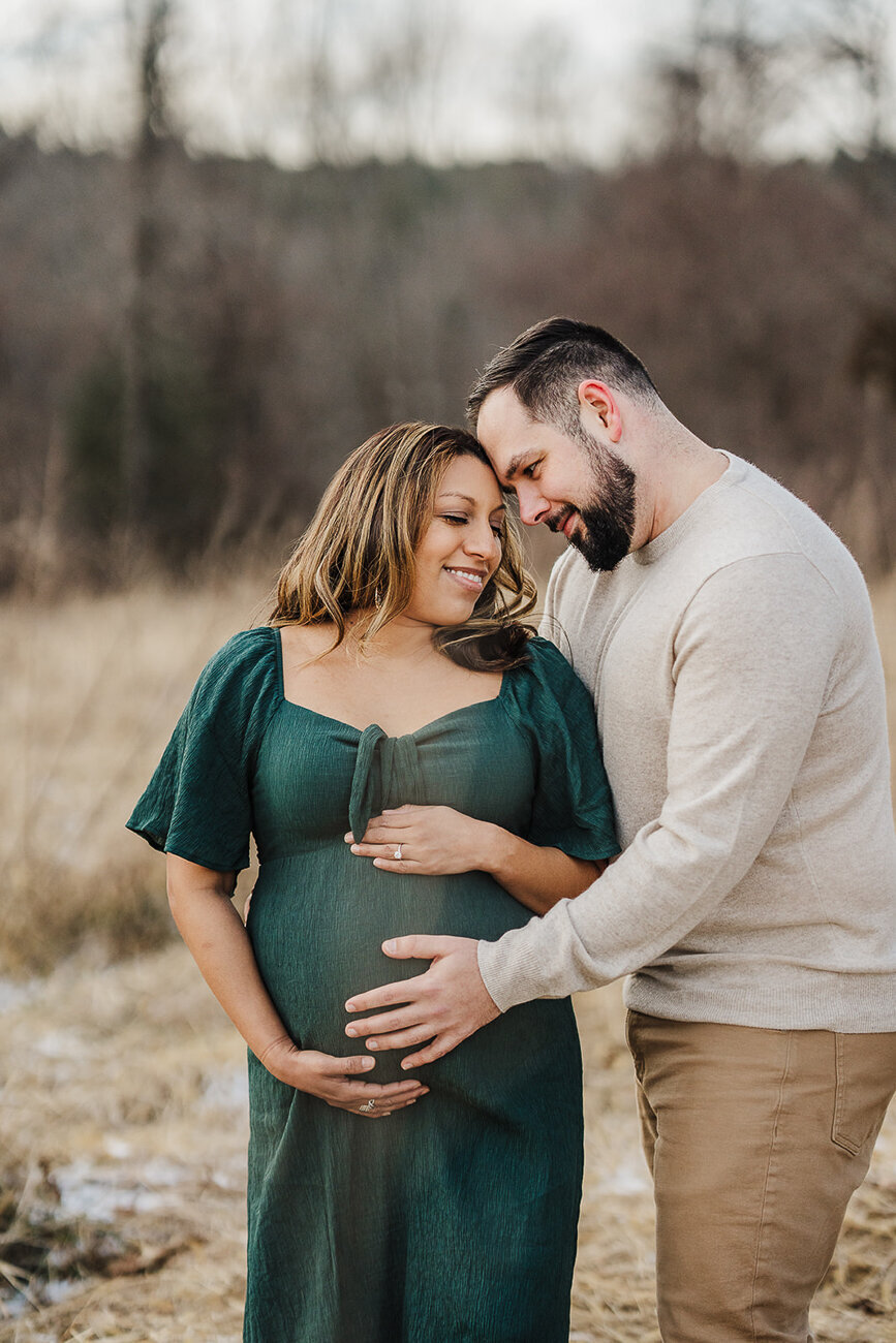 couple stands forehead to forehead during winter maternity photos in boston