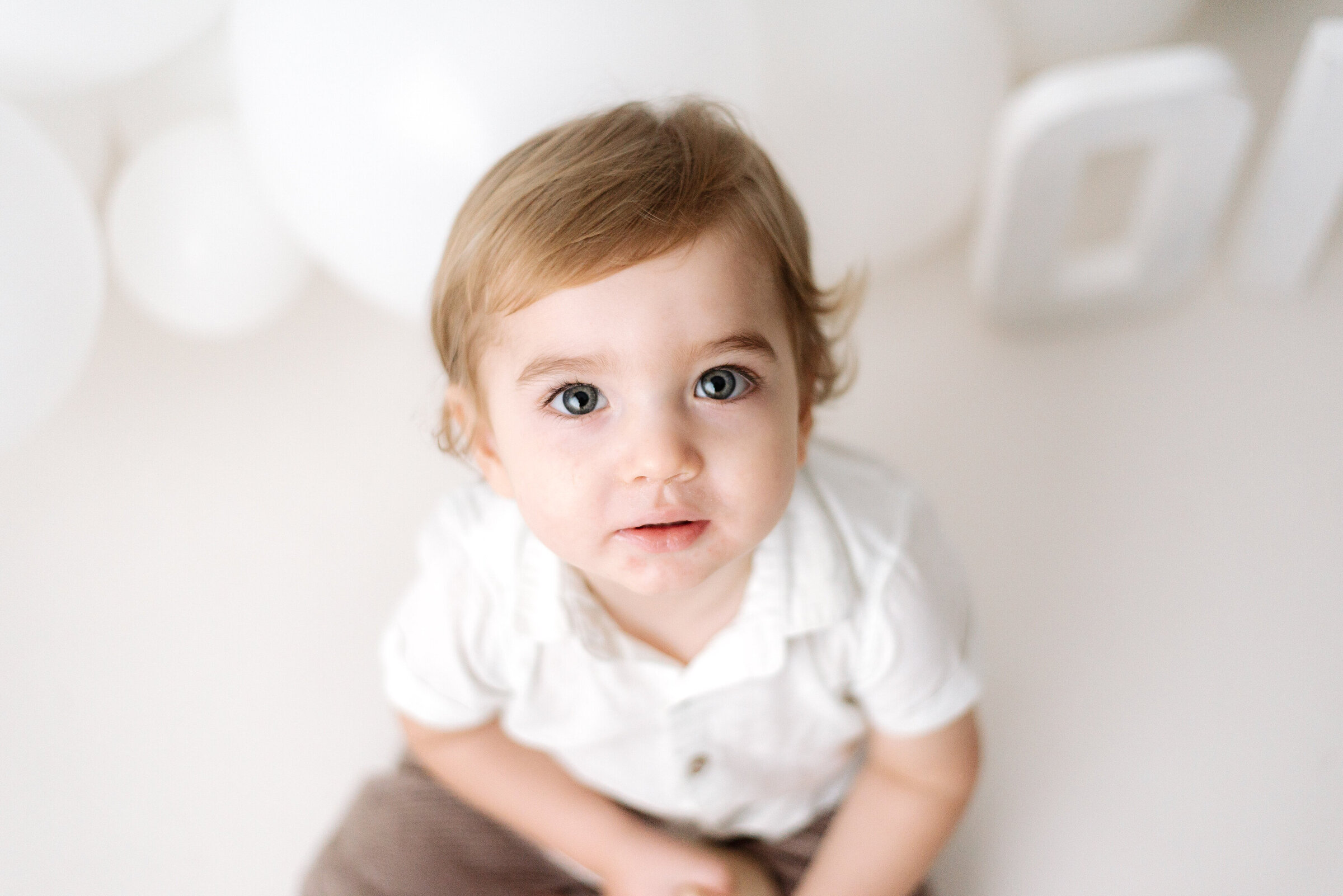 Little boy sitting on the floor looking up at billingshurst cake smash photoshoot