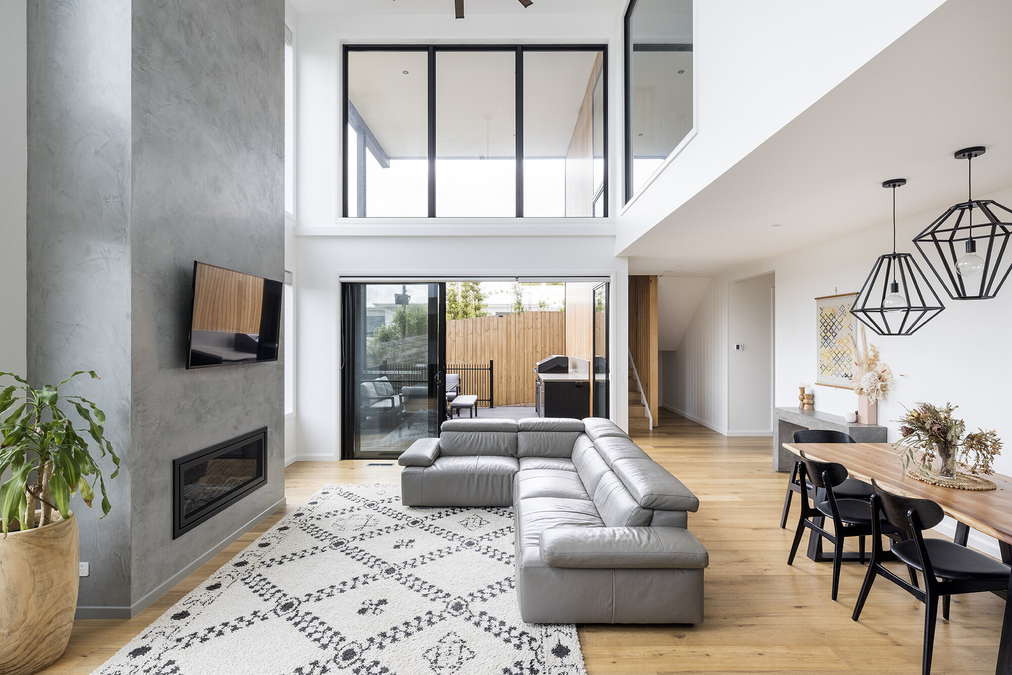 high ceiling black window frames leather couch and timber floor