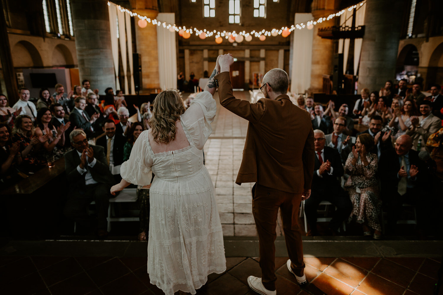 Married couple raise their hands at their wedding at Left Bank in Leeds.