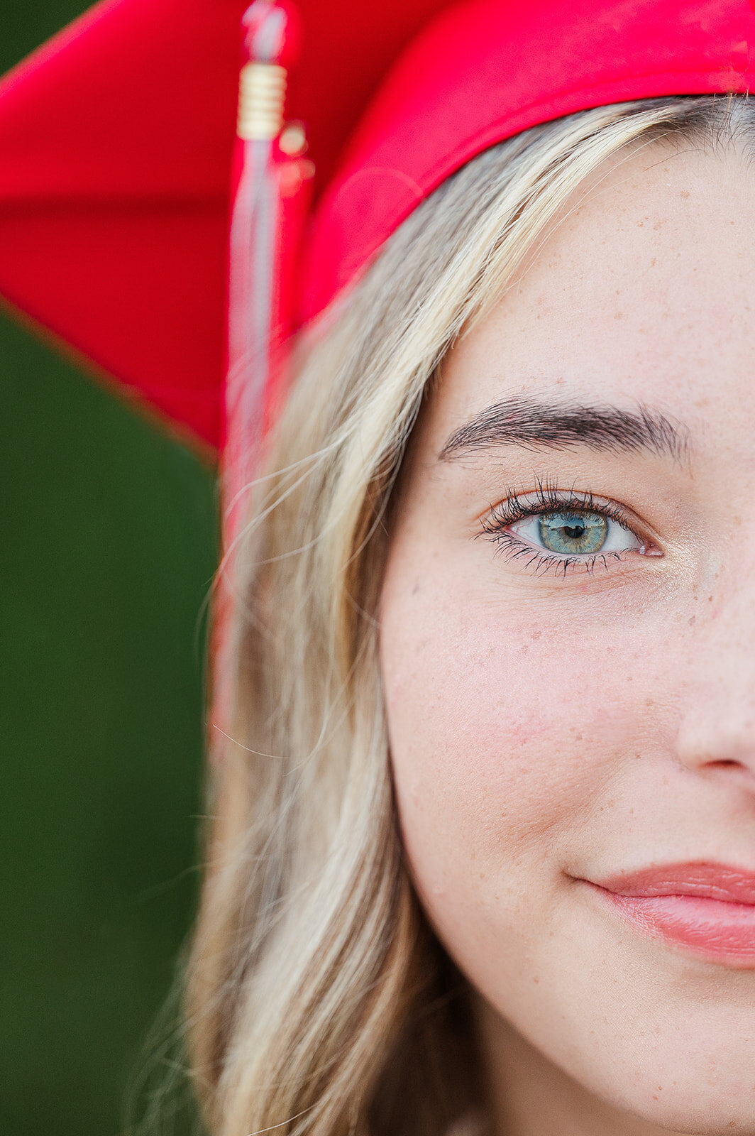 Tight crop of a senior girl's blue eyes wearing a red graduation cap