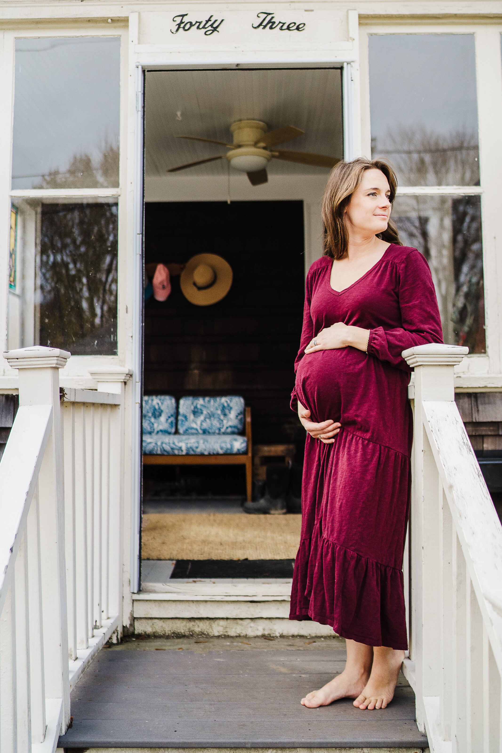 pregnant woman in purple dress stands on front porch