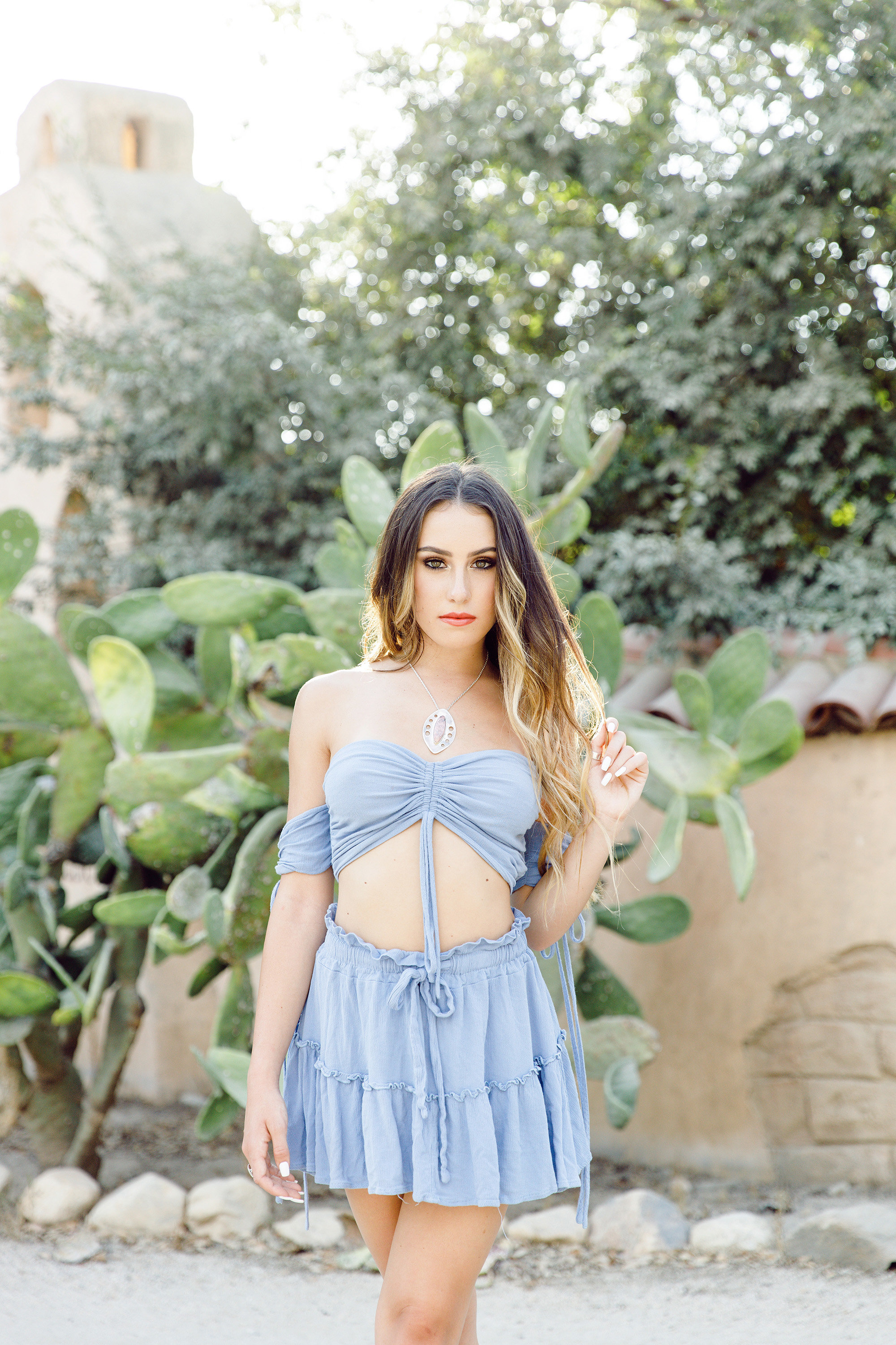 Santa Clarita senior portraits with stylish teen girl in blue two-piece outfit standing by cactus, boho fashion-inspired photography