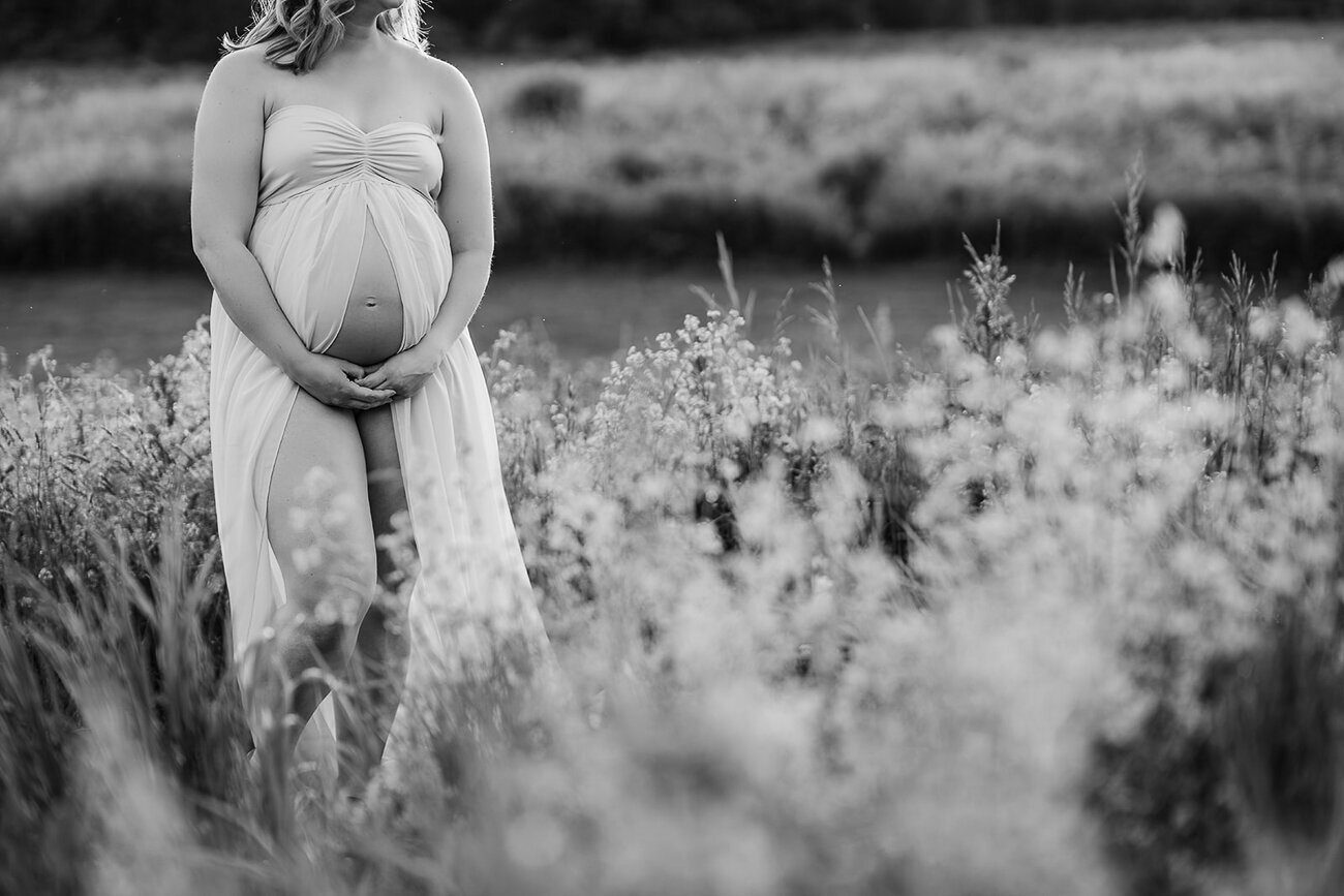 black and white image of bare belly maternity photos in a field