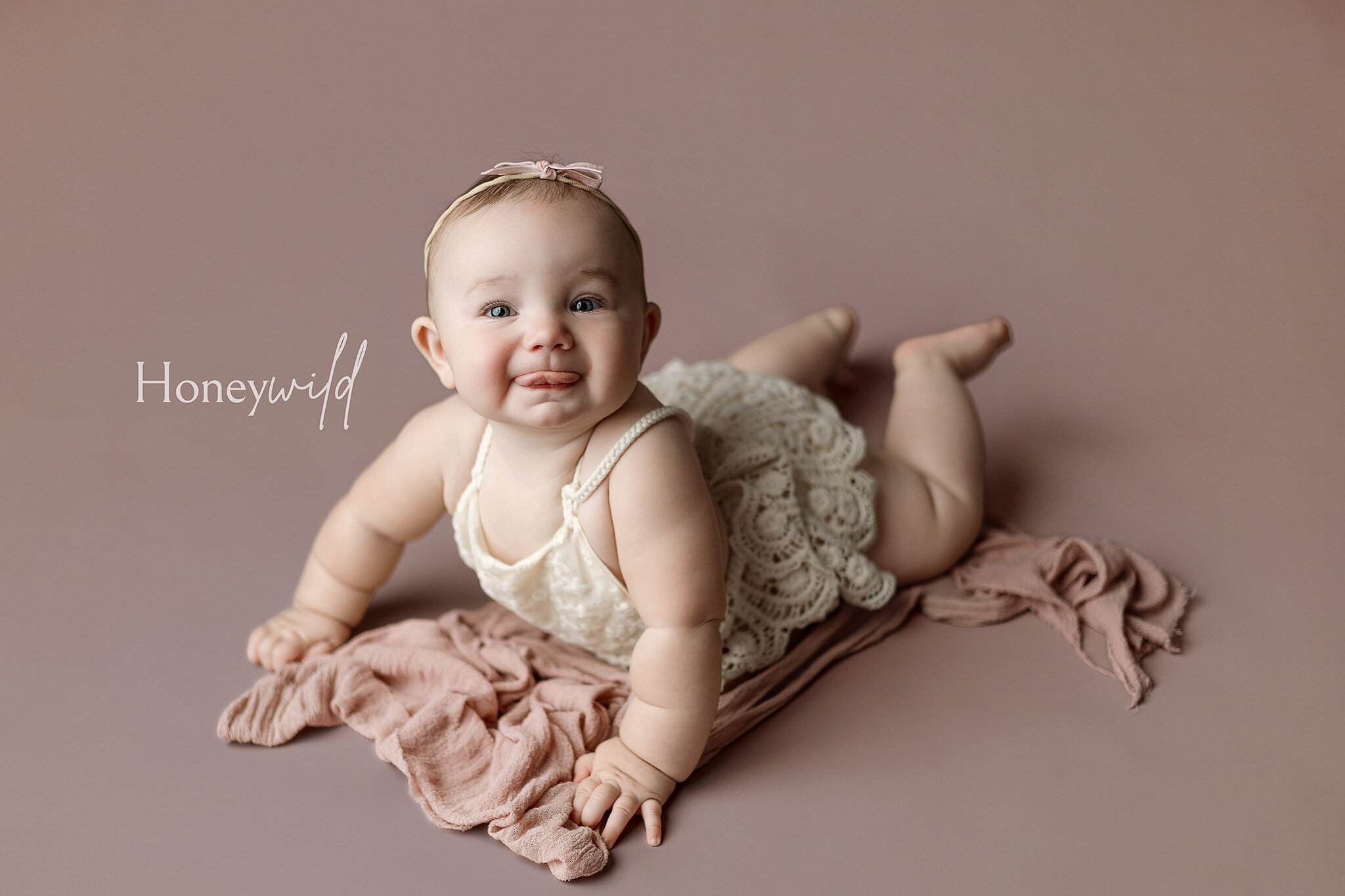 Grand Rapids newborn baby photography by Honeywild Photo: smiling six month old sitting on a mint chair backwards on a beautiful rich blue background with a wooden stacking toy near his feet