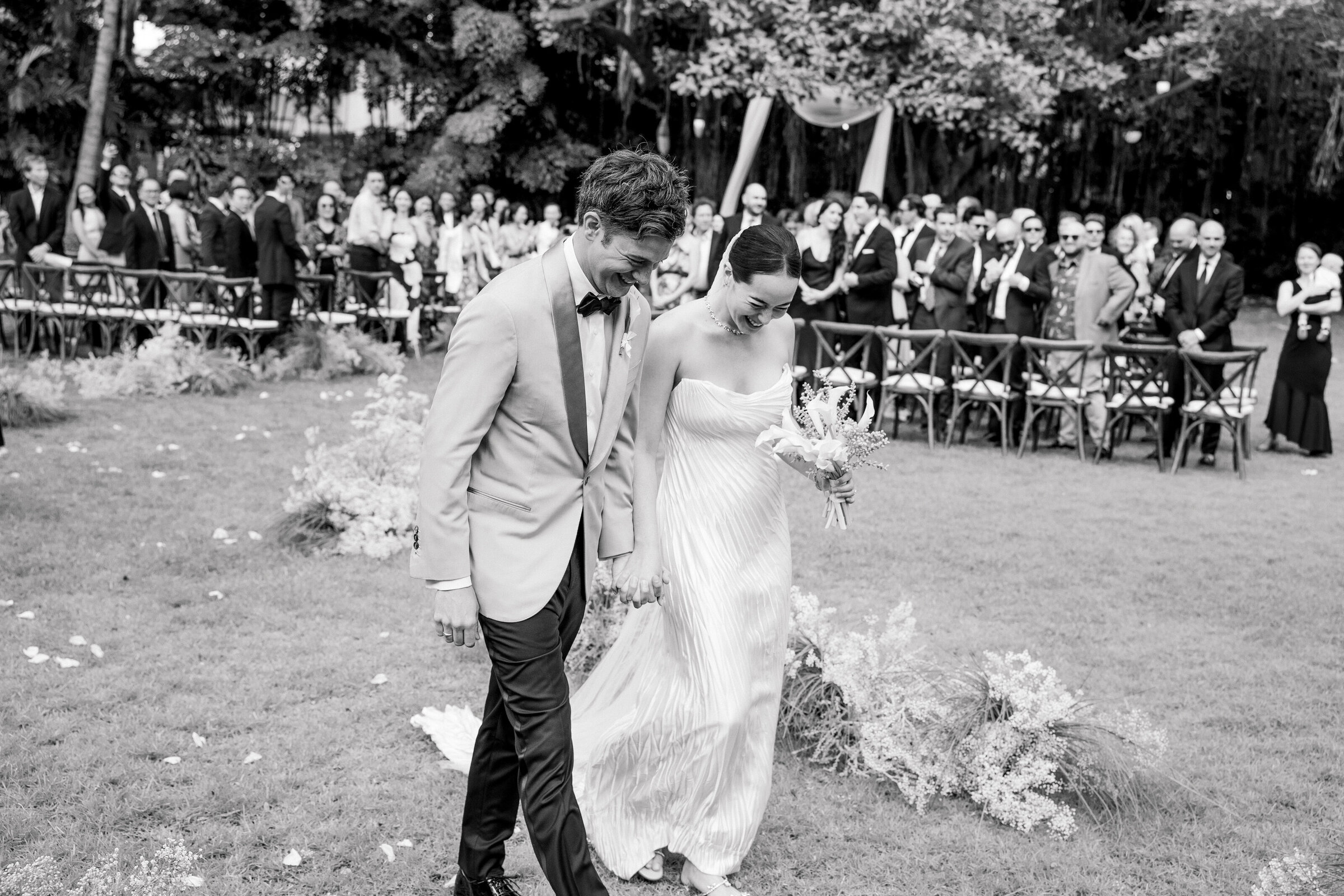Wedding and Elopement Photographer, black and hite image of couple walking past the crowd at ceremony