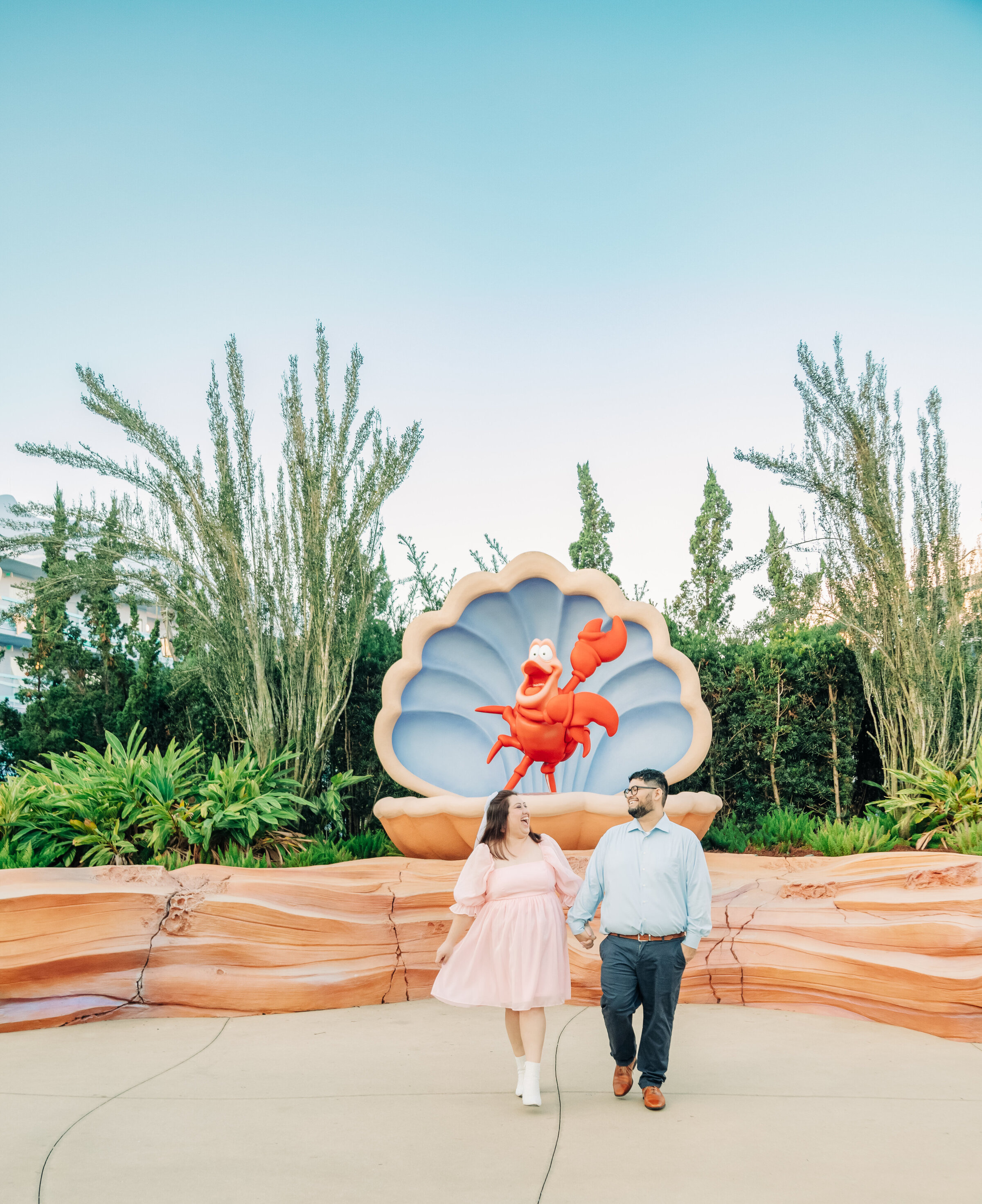 Engaged couple walking holding hands and laughing at Disney's resort