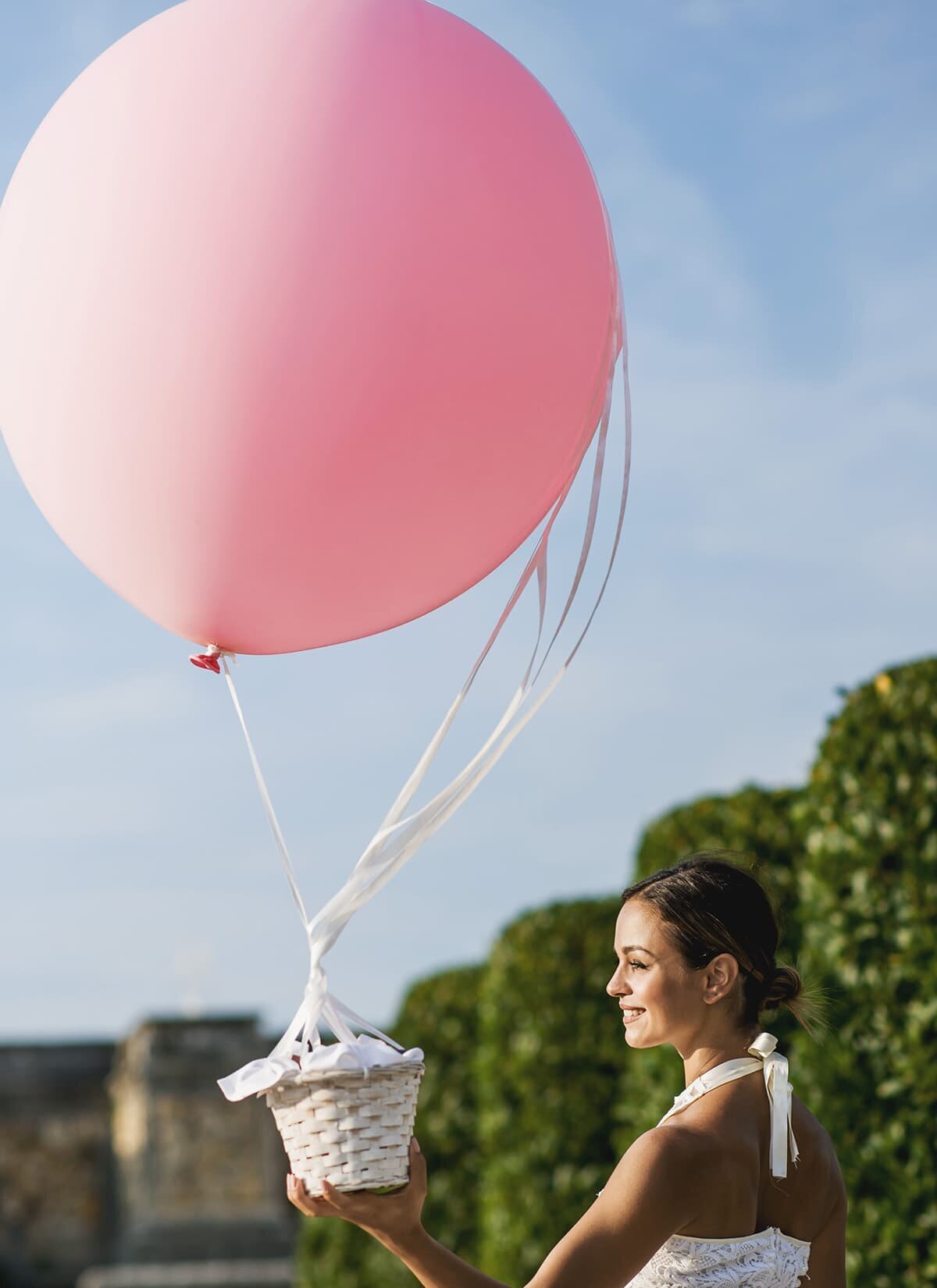 Woman holding basket tied to large balloon