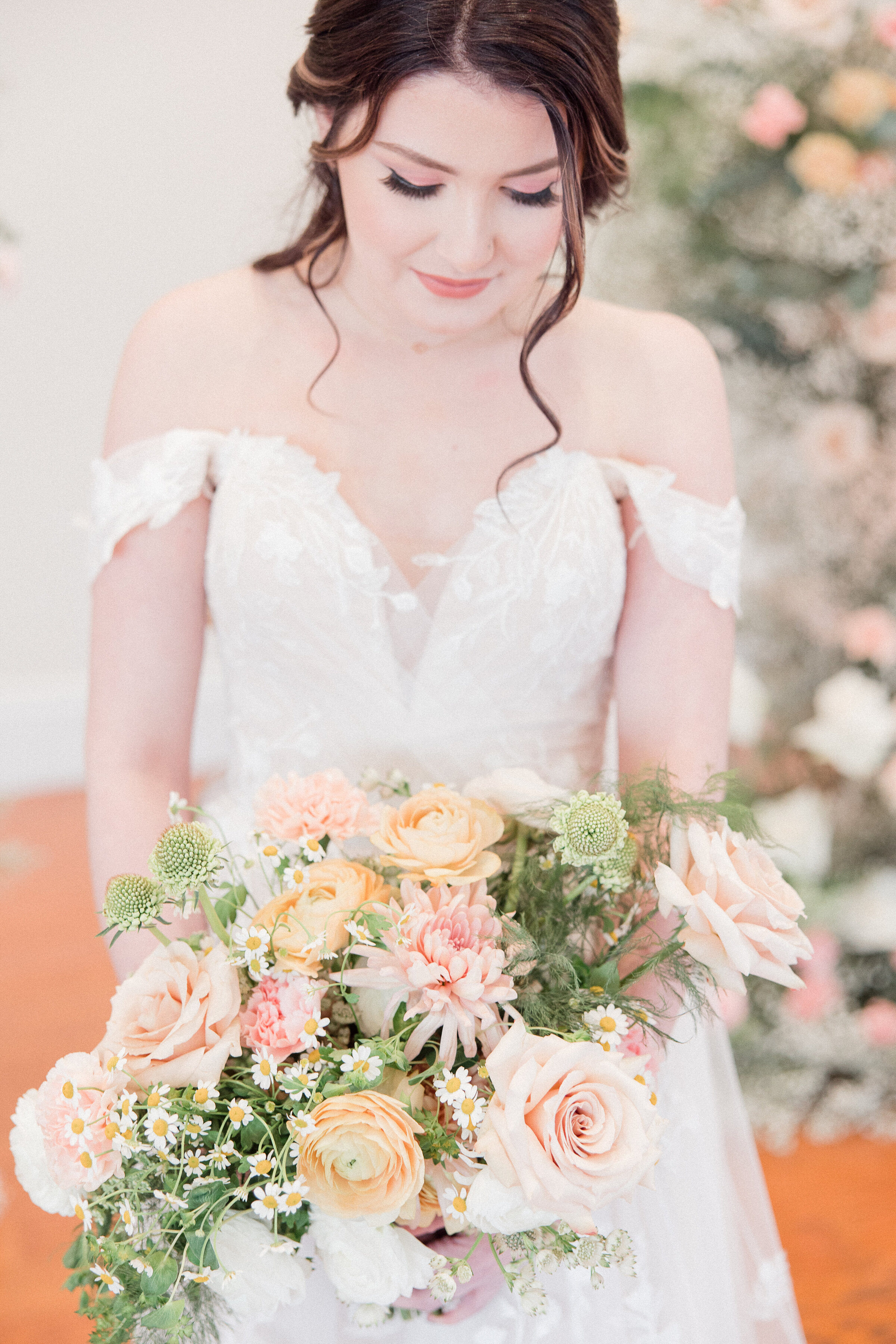 bride smiling down at bouquet