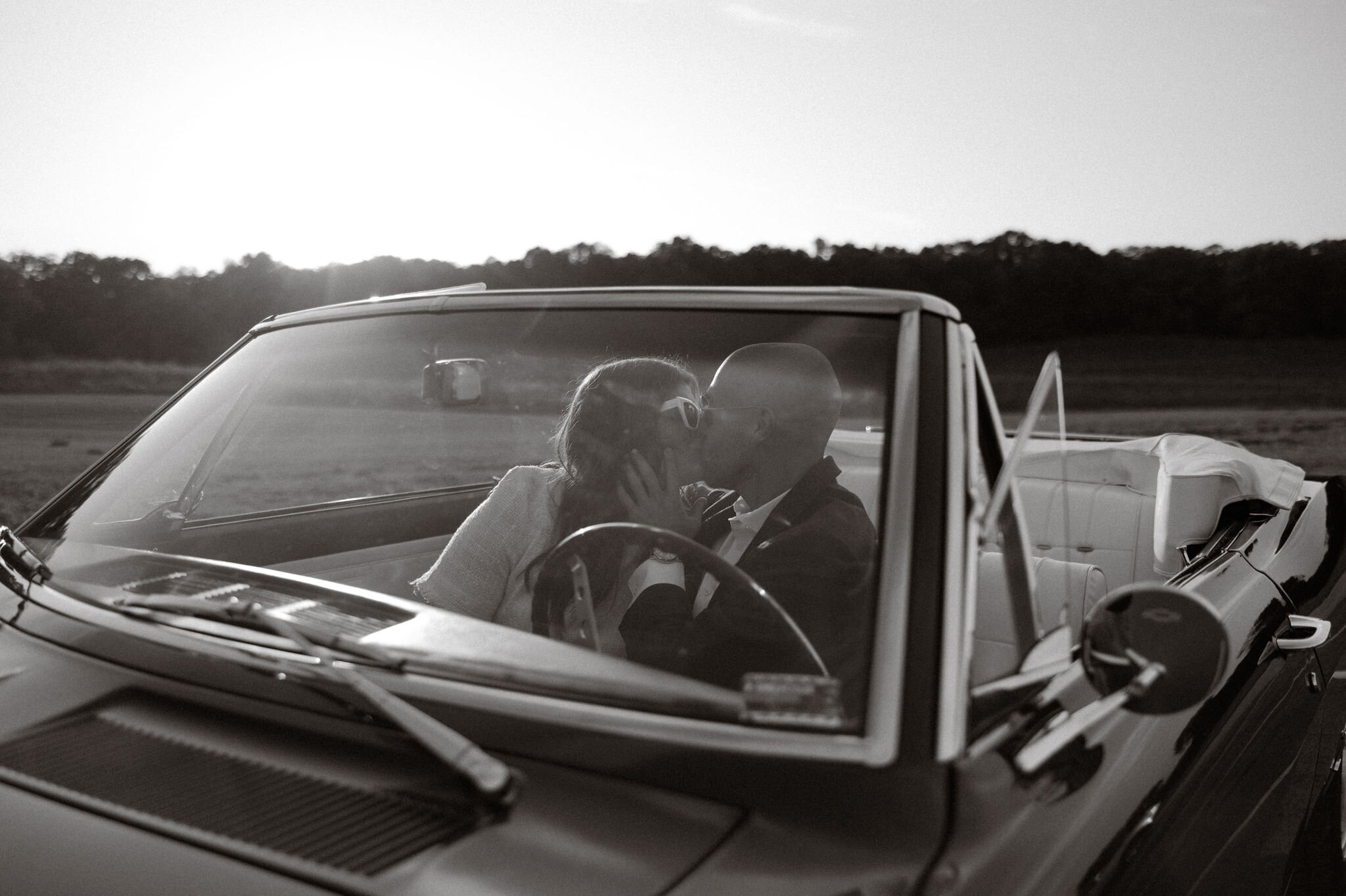 Amazing black and white vintage looking engagement photo of bride and groom sitting in a classic convertible kissing captured by Morgan Ashley Lynn Photography in Madison,  WI