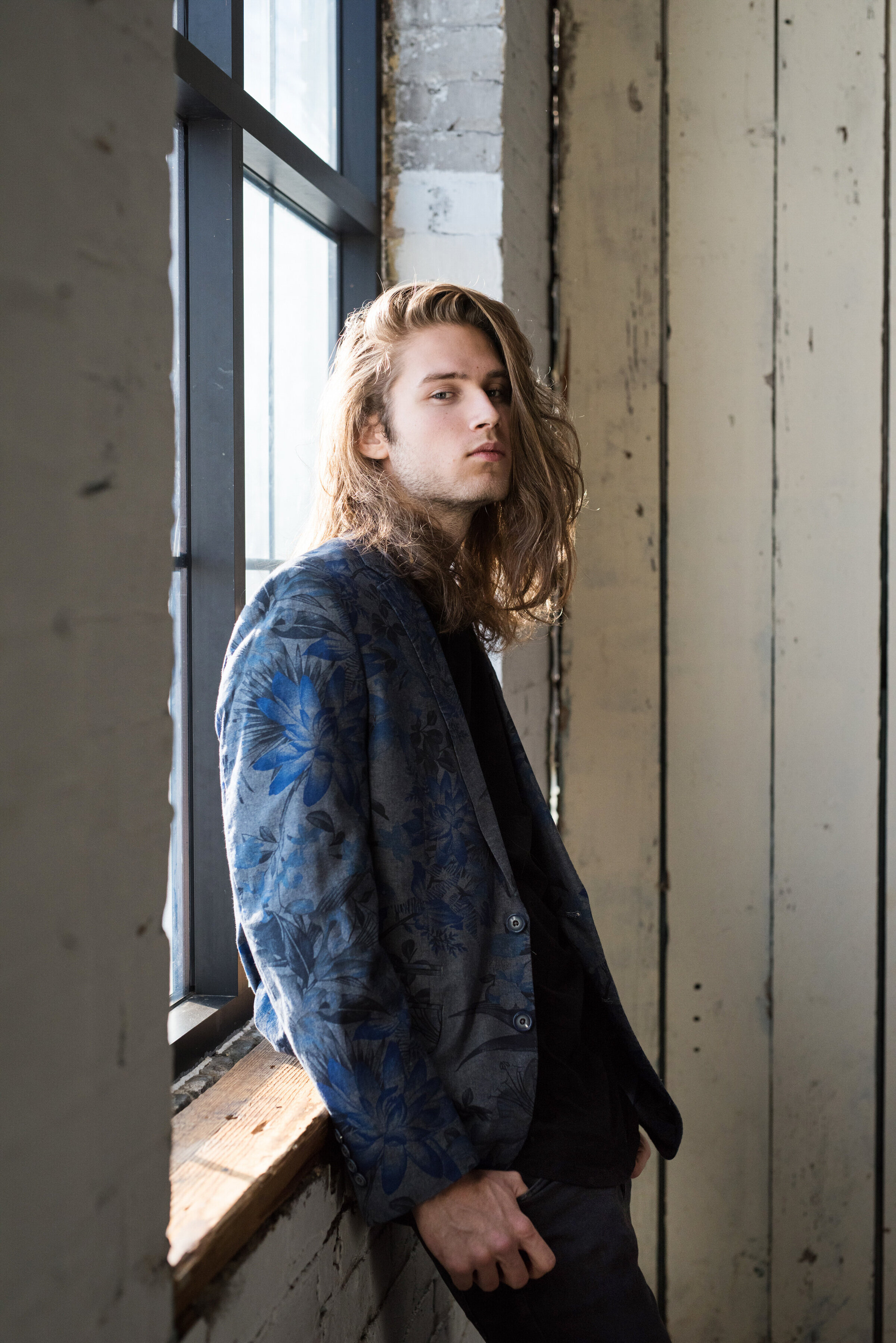 St. Paul Minnesota high school senior photo of guy leaning against the window in warehouse studio