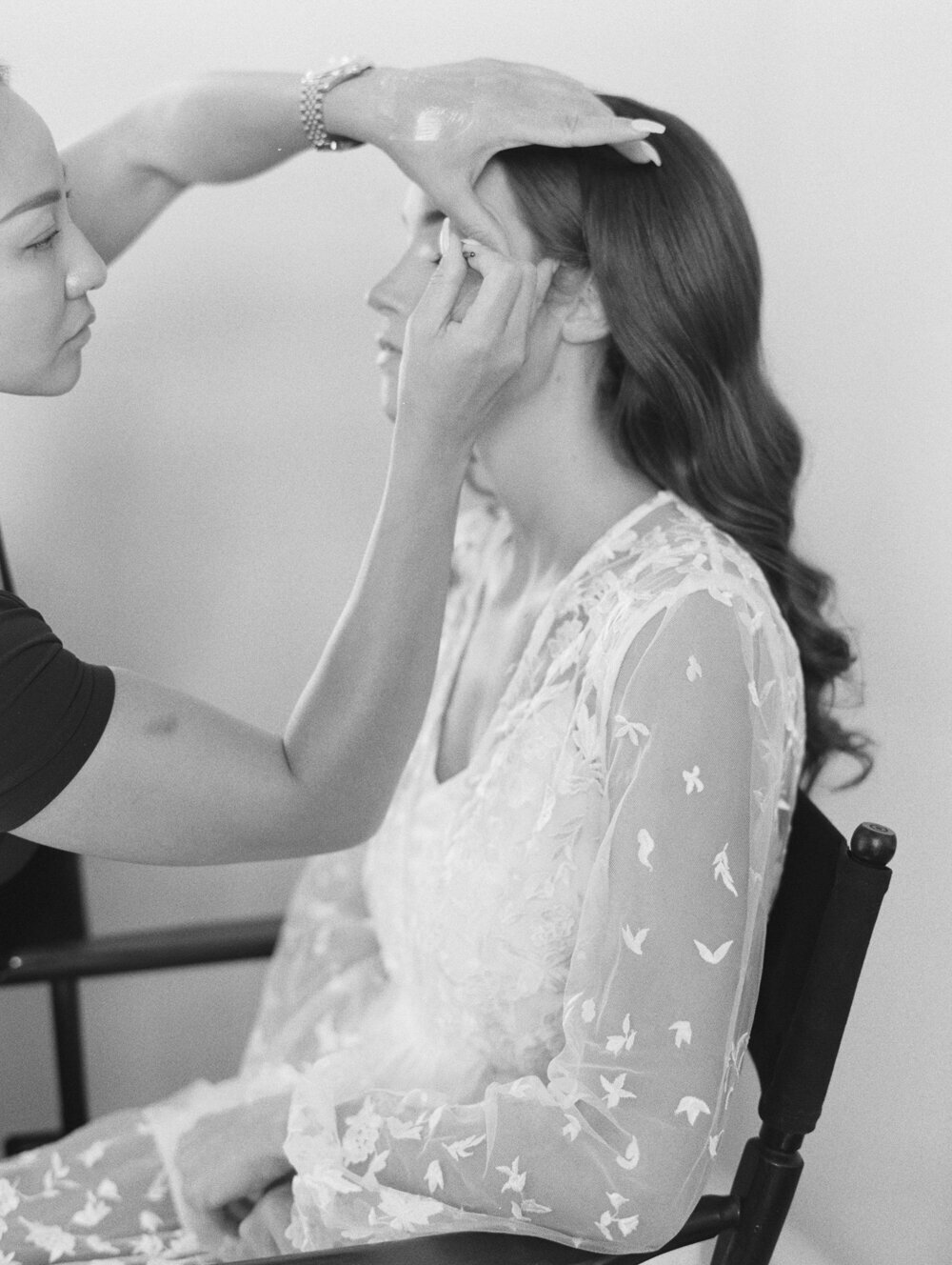 bw film photo of bride getting her makeup done