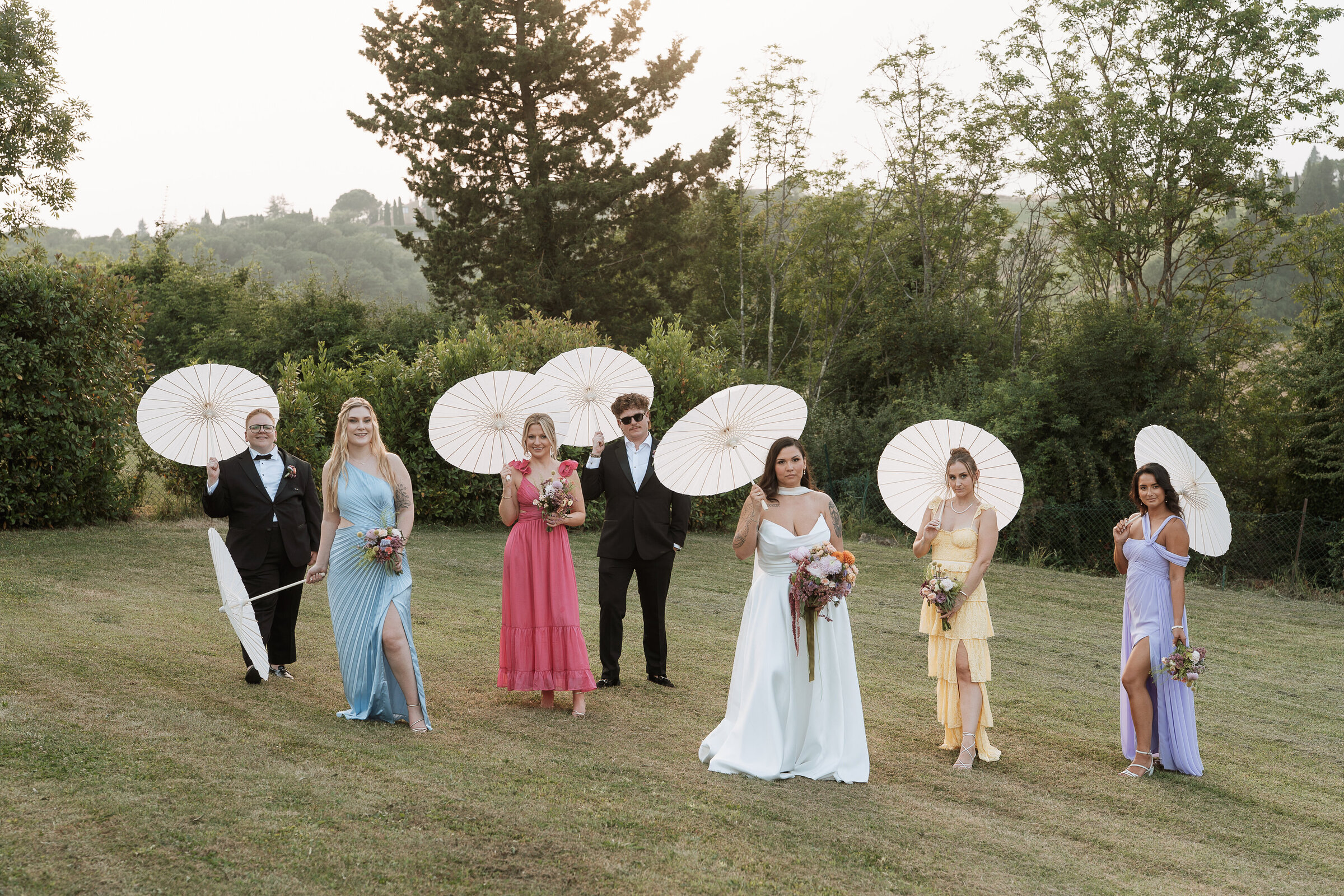 Bridal party editorial group shot on lawn at Tuscany wedding villa holding parasols  