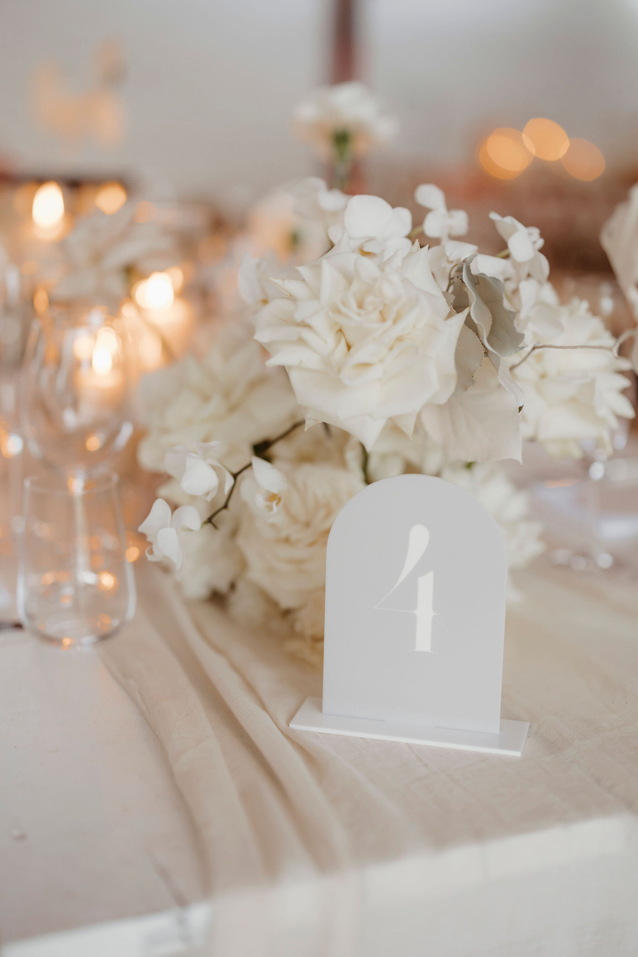 An arched modern table number in mushroom colour on a wedding table at Masseria Moroseta