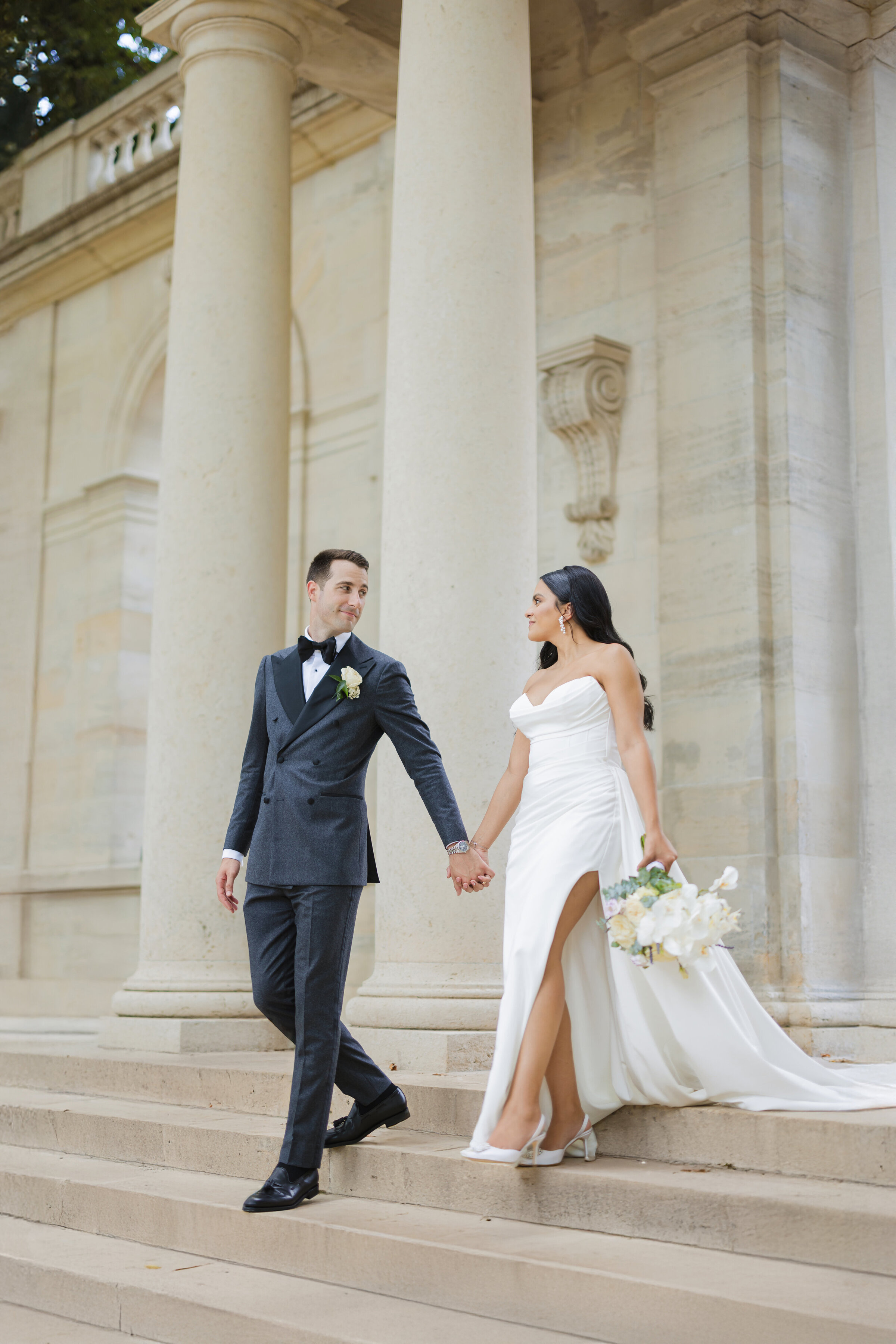Timeless and elegant multicultural couple walking down the steps of the Rodin Museum during their luxury wedding day in Philadelphia

