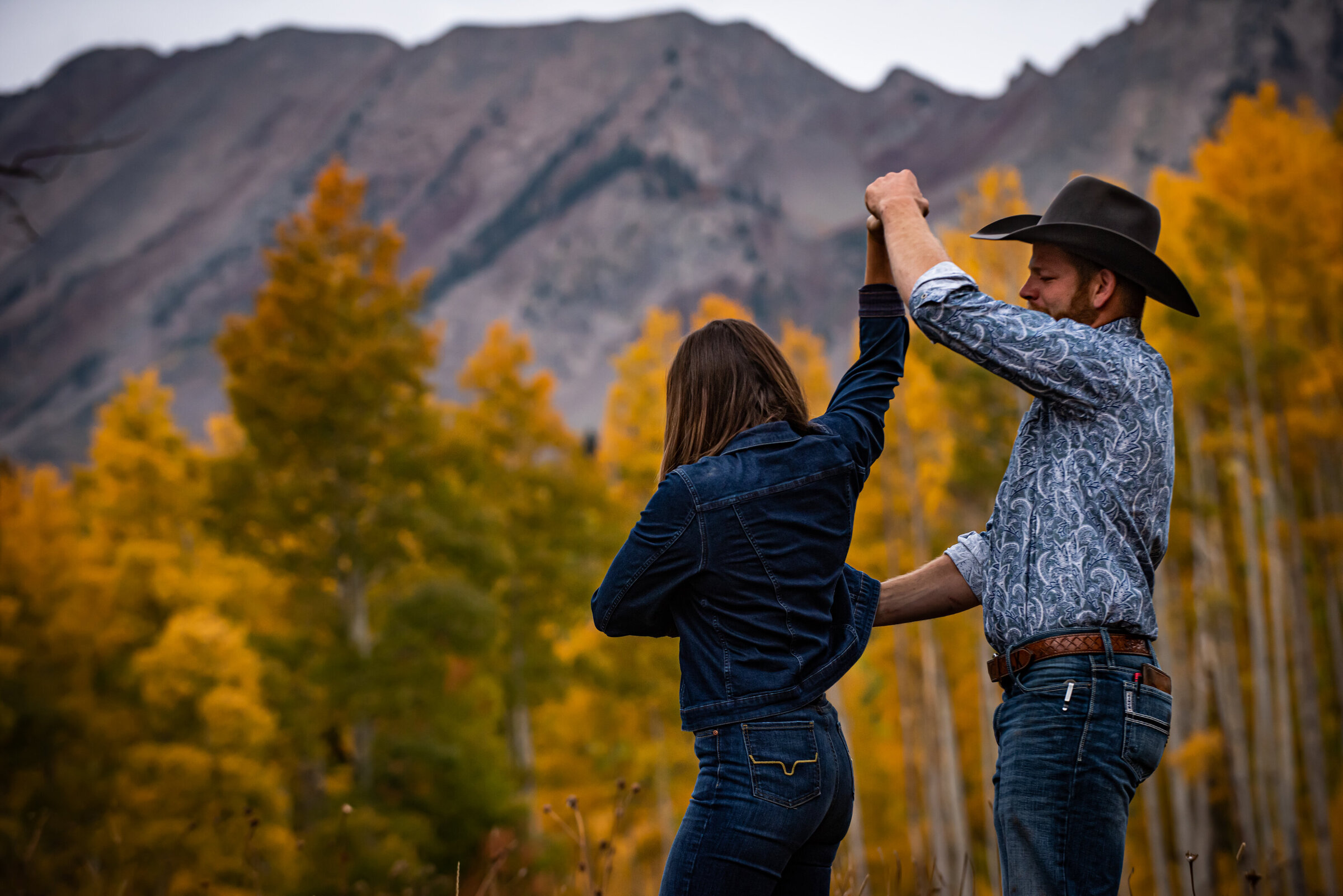 Cowboy dances with fiance in aspen grove in autumn