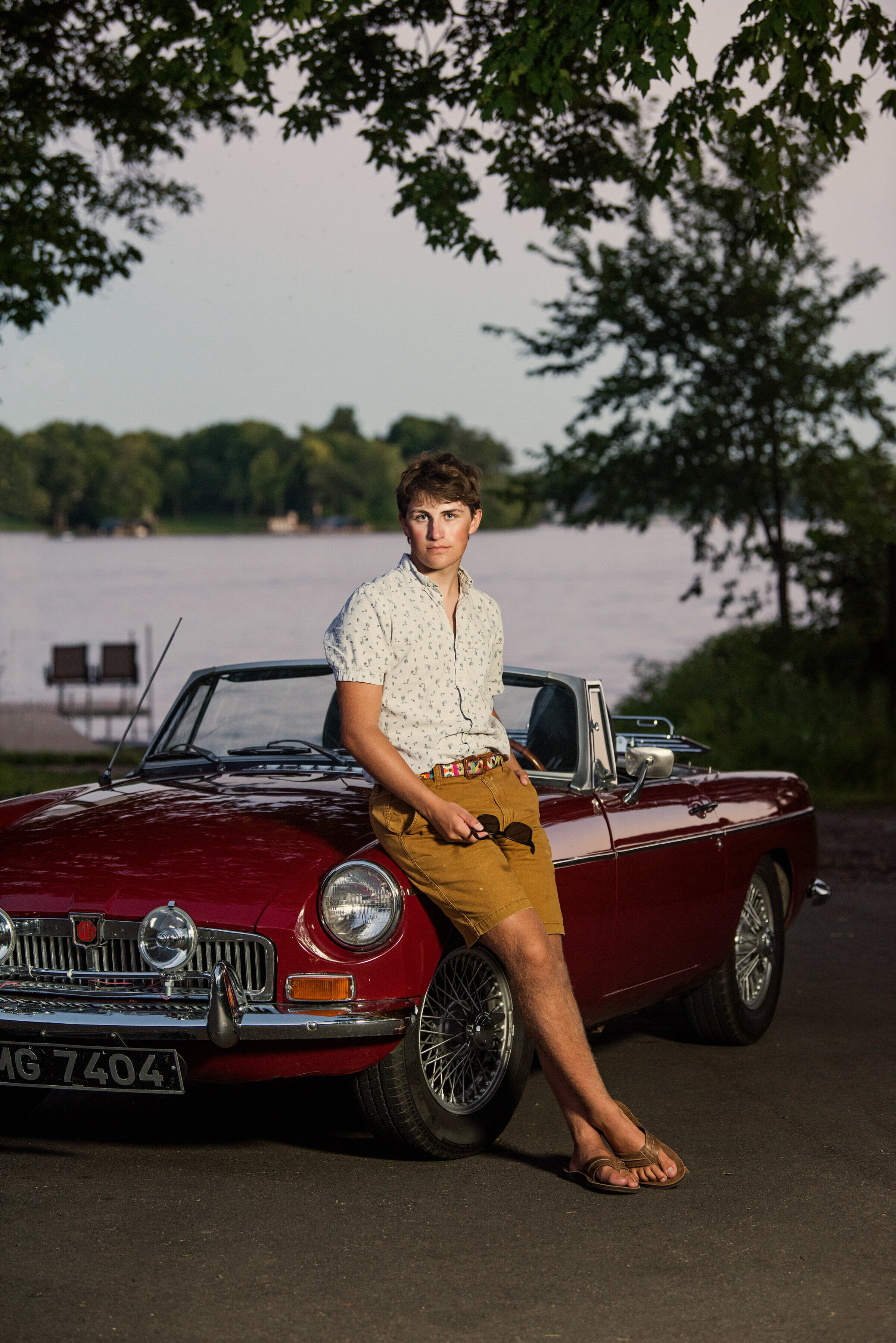 high school senior photo of boy leaning against vintage car in front of Lake Minnetonka in minnesota