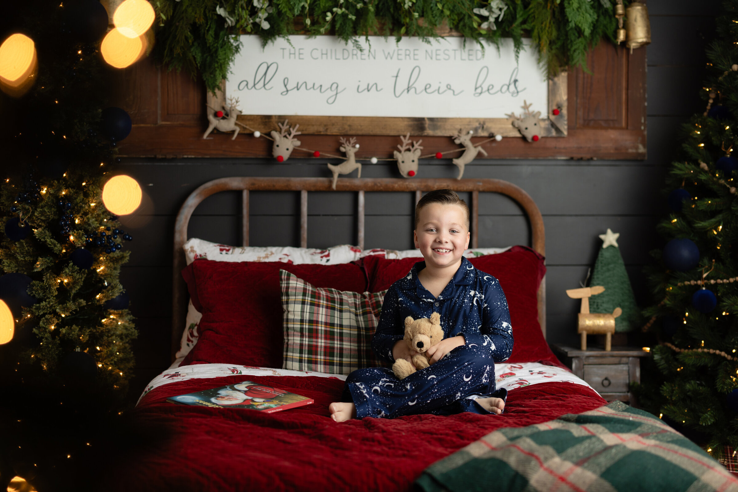 Child sitting on a cozy holiday bed during a Christmas pajama mini-session at a Canton, GA photography studio