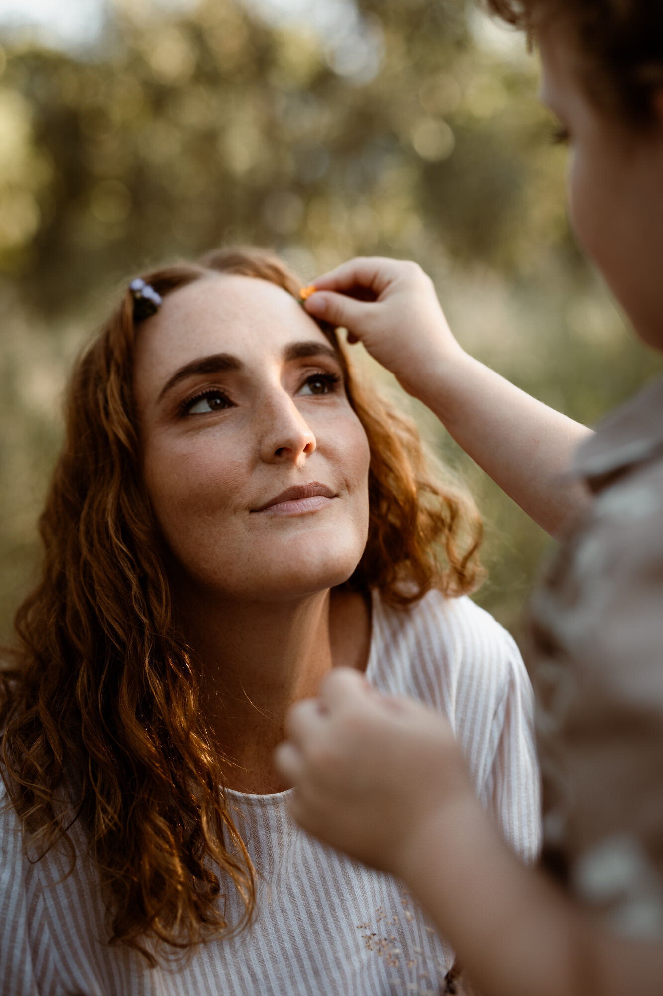 Son putting a flower in his mother's hair and Brisbane Family Photoshoot location