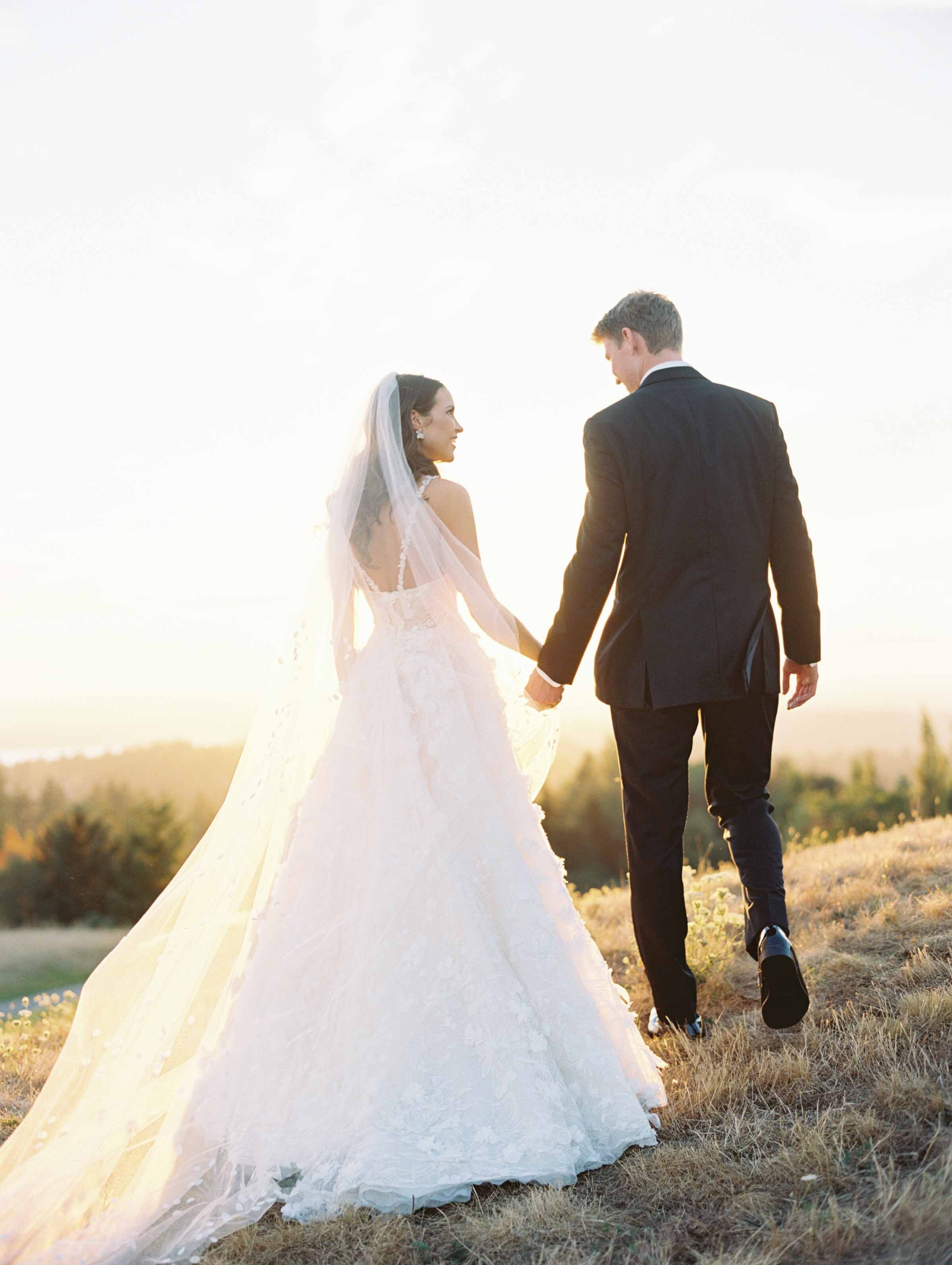 bride and groom walk into the sunset light holding hands