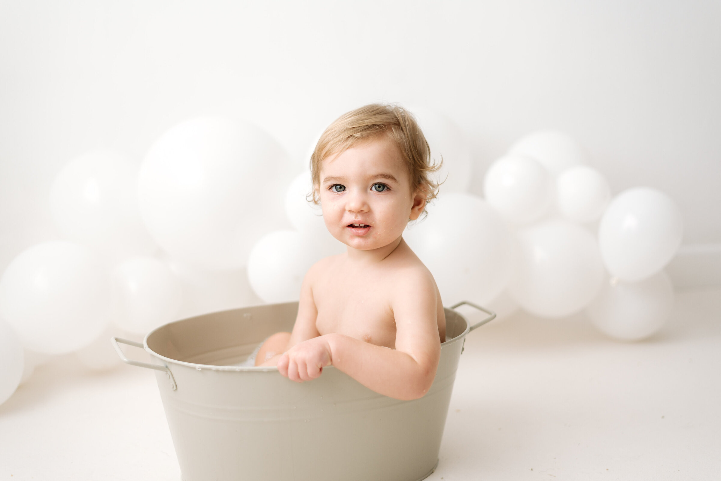 Baby boy sitting in a little bath tub at Billingshurst cake smash photoshoot