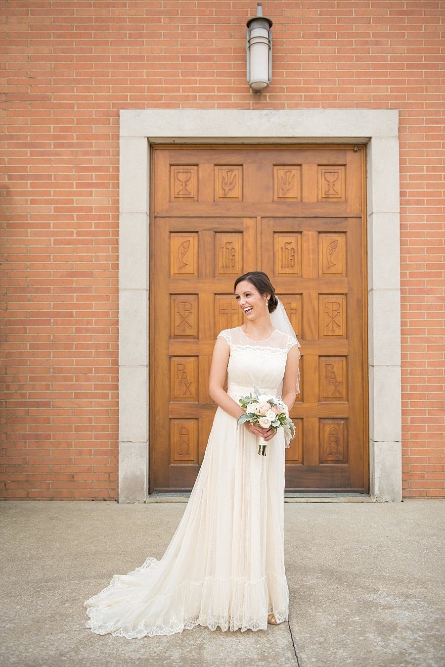 Bride wearing her mothers vintage dress in front of iconic wooden doors at St Henrys Cathedral