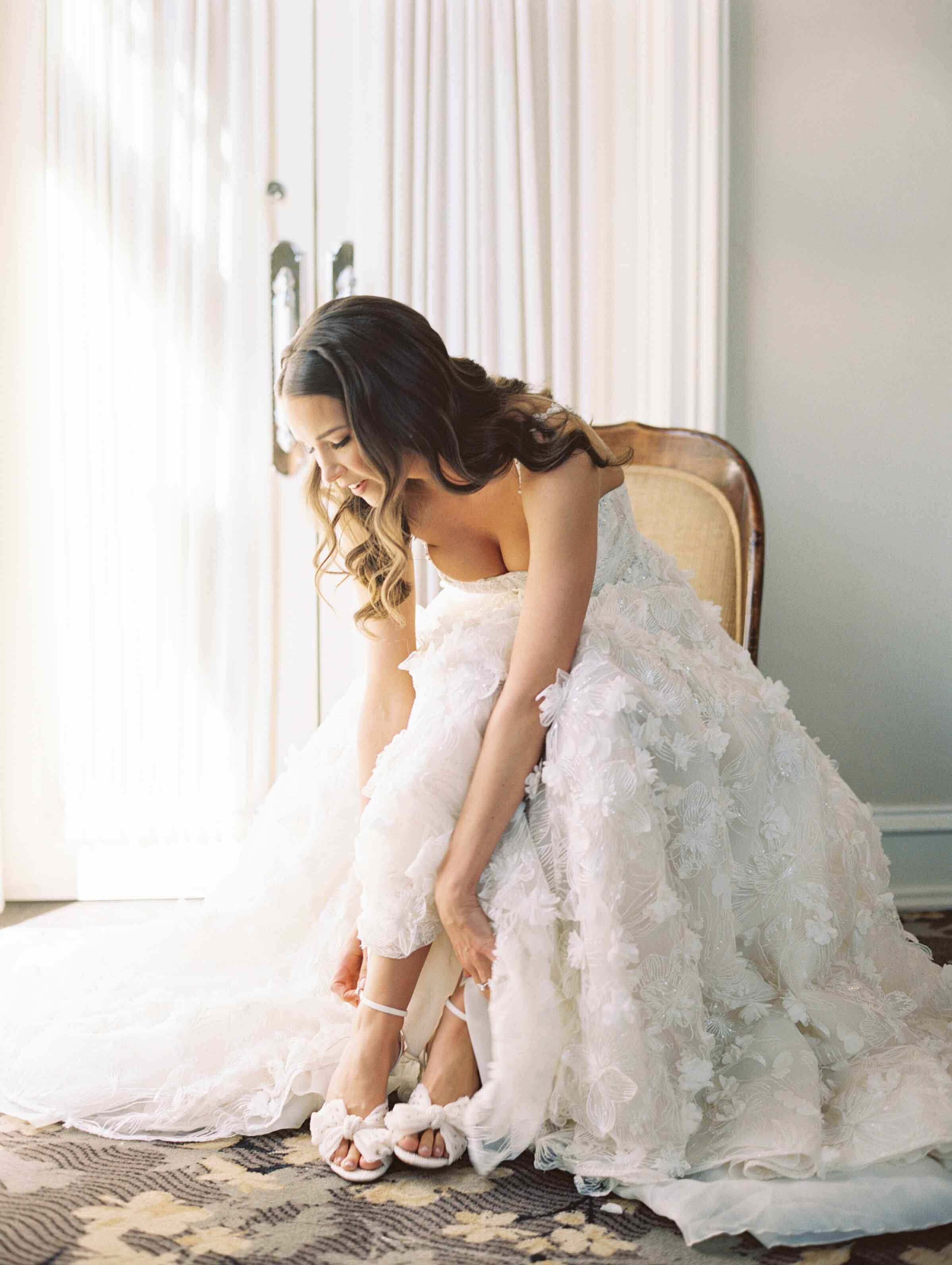 bride putting shoes on in galia lahav gown