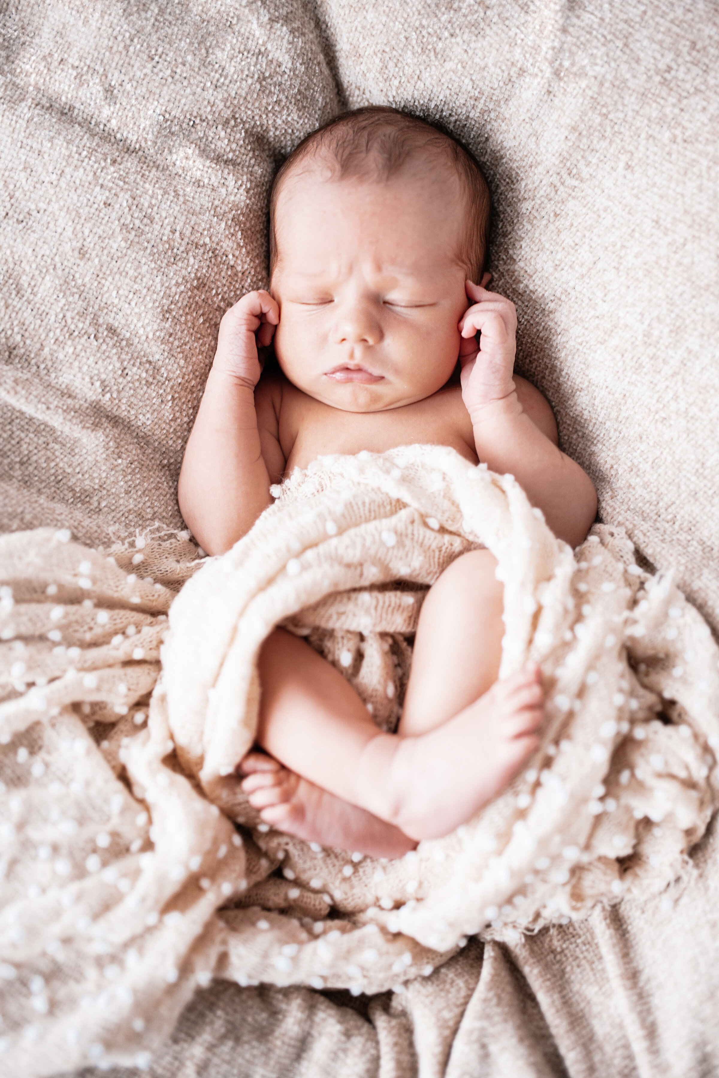 Newborn baby sleeping whilst wrapped in blankets