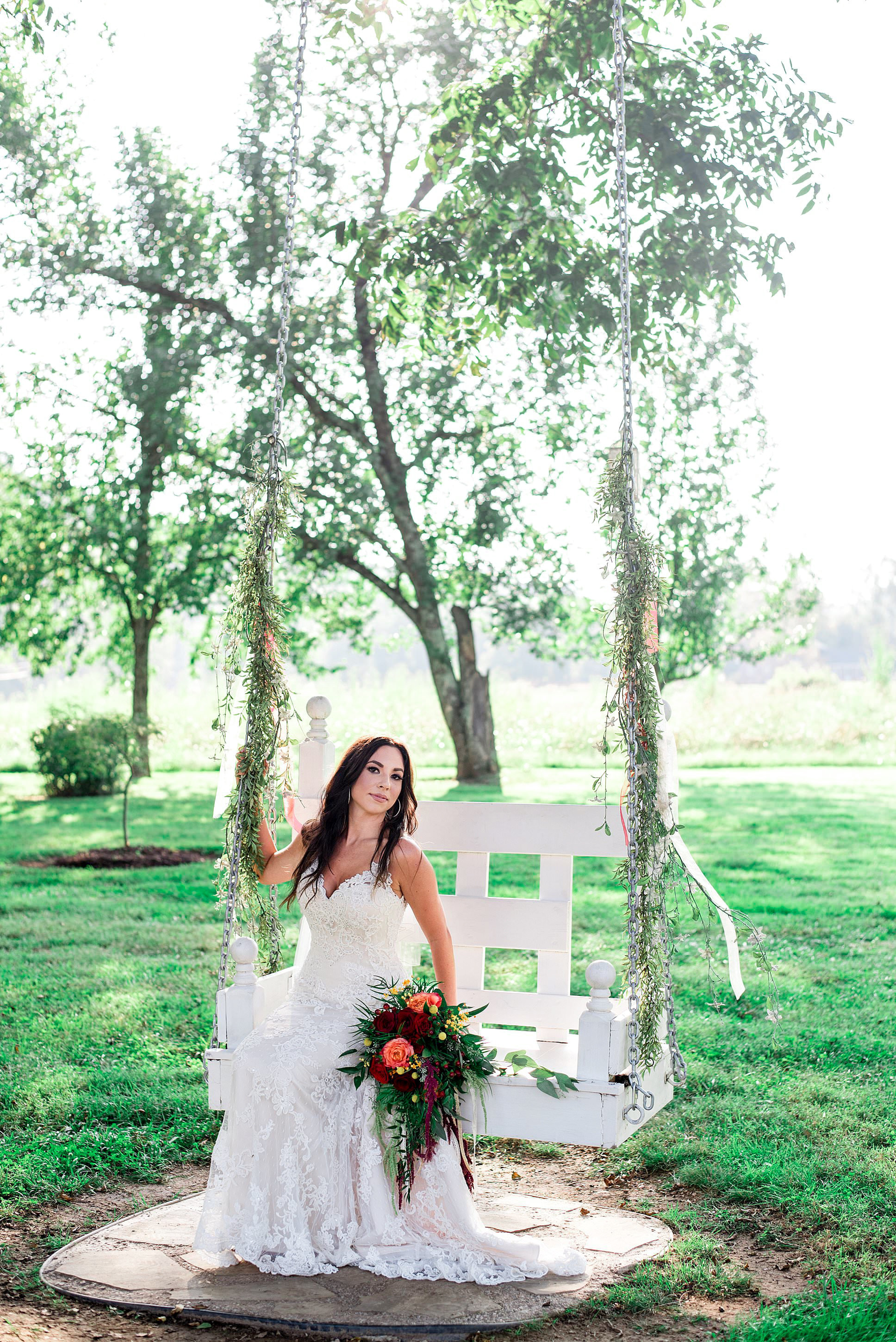 Romantic portrait of bride sitting on a white bench swing at Dakewood Farms