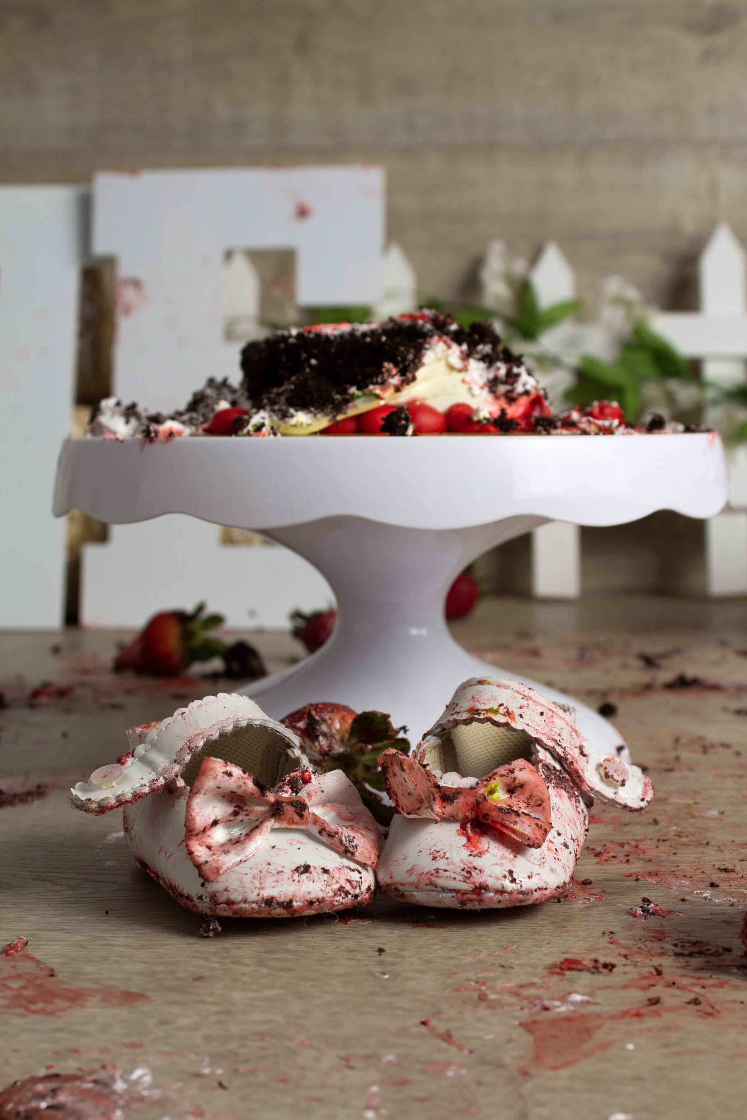 Image after a cake smash session in Minot, North Dakota. The white shoes are dirty with red and white frosting. There are also bits of black cake on them.