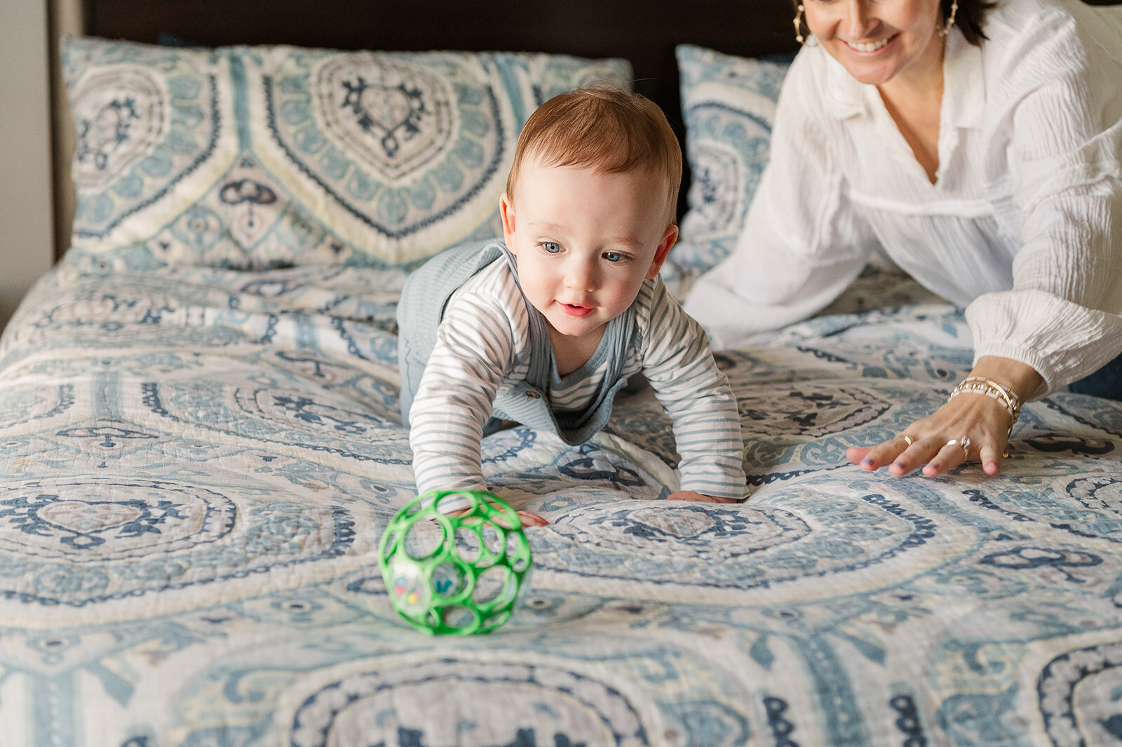 Little boy playing with a green toy truck on his bed during a relaxed in-home family session in York, Pennsylvania.