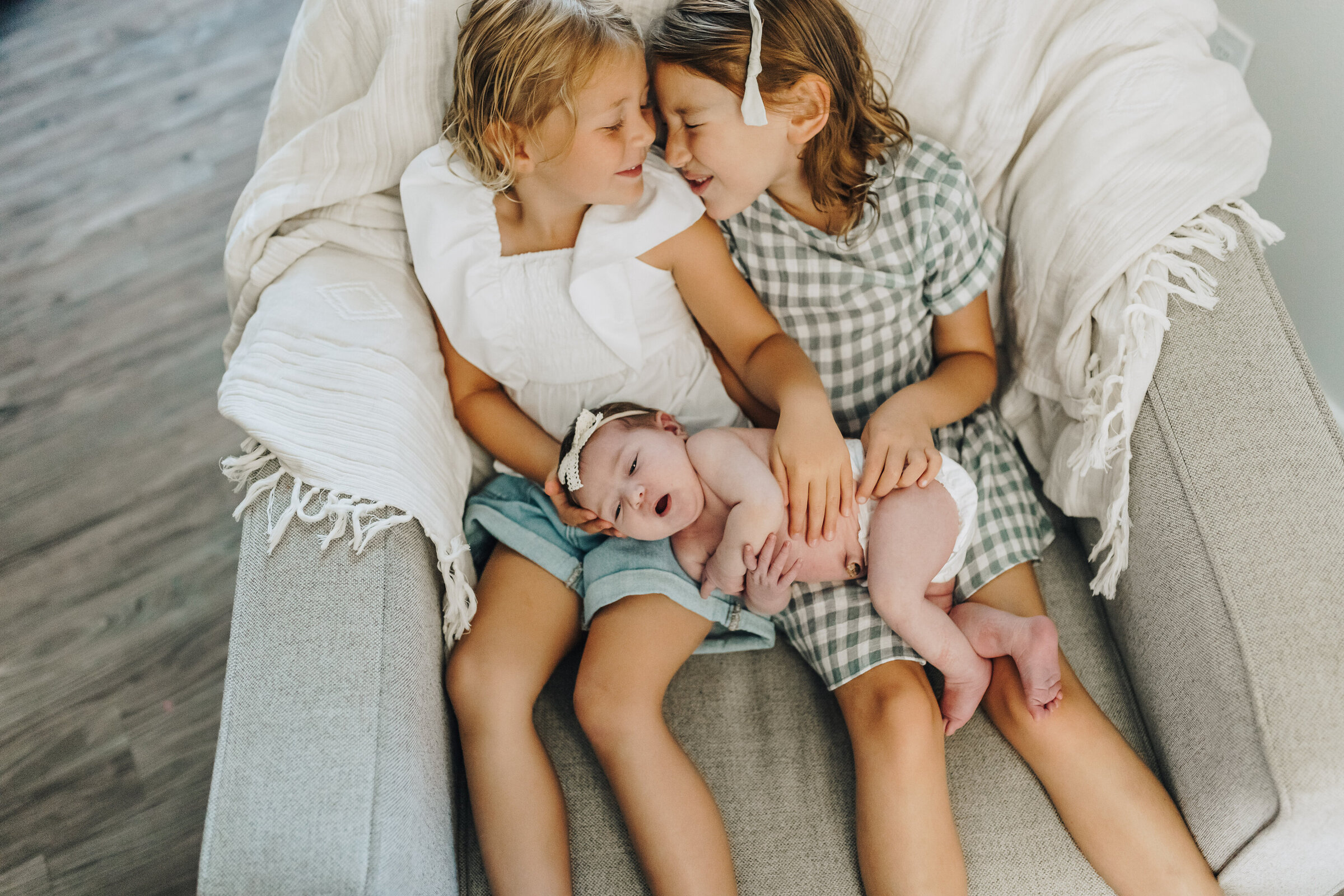 Older Sisters Snuggle Baby Sister