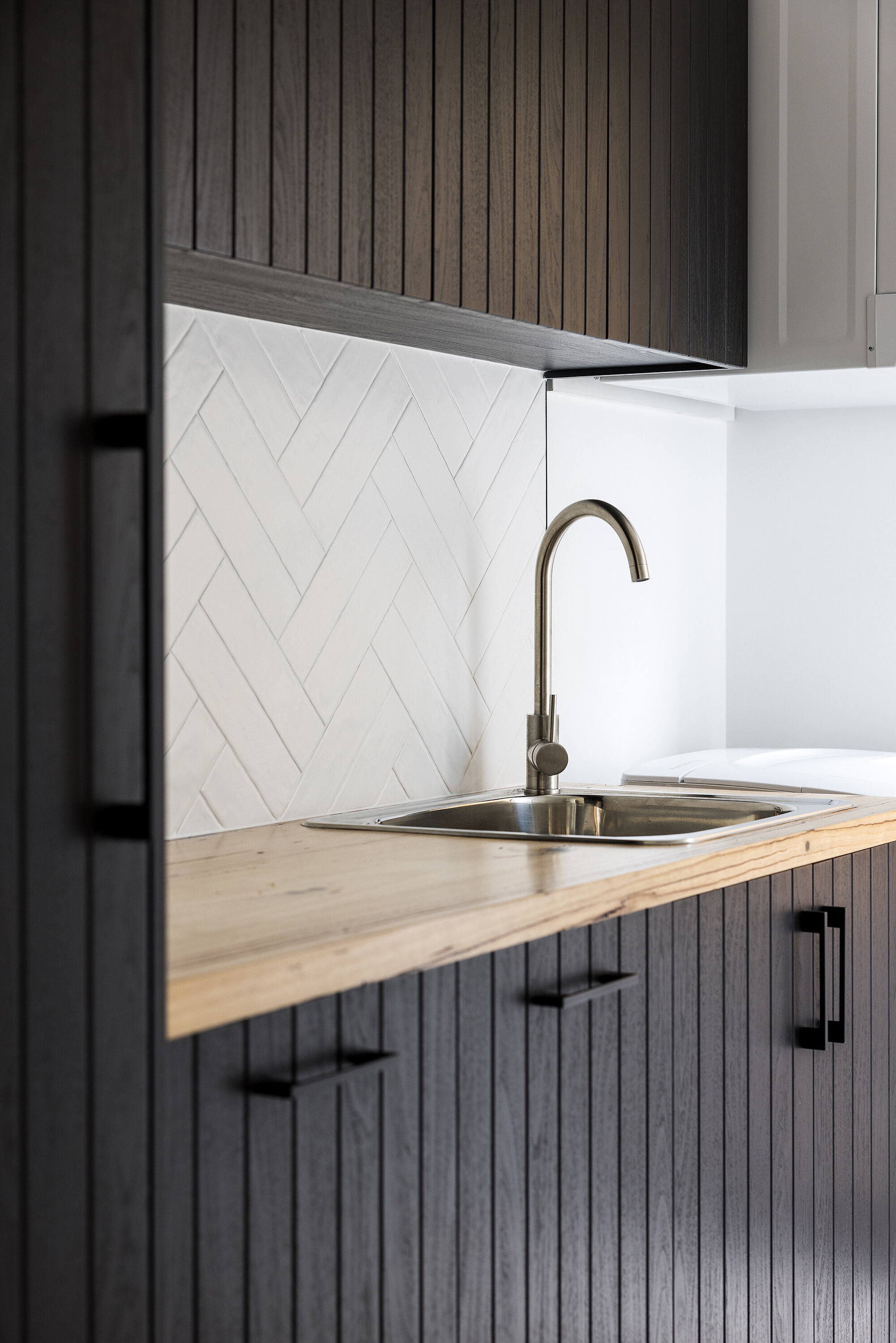 Black cabinetry herringbone white tile