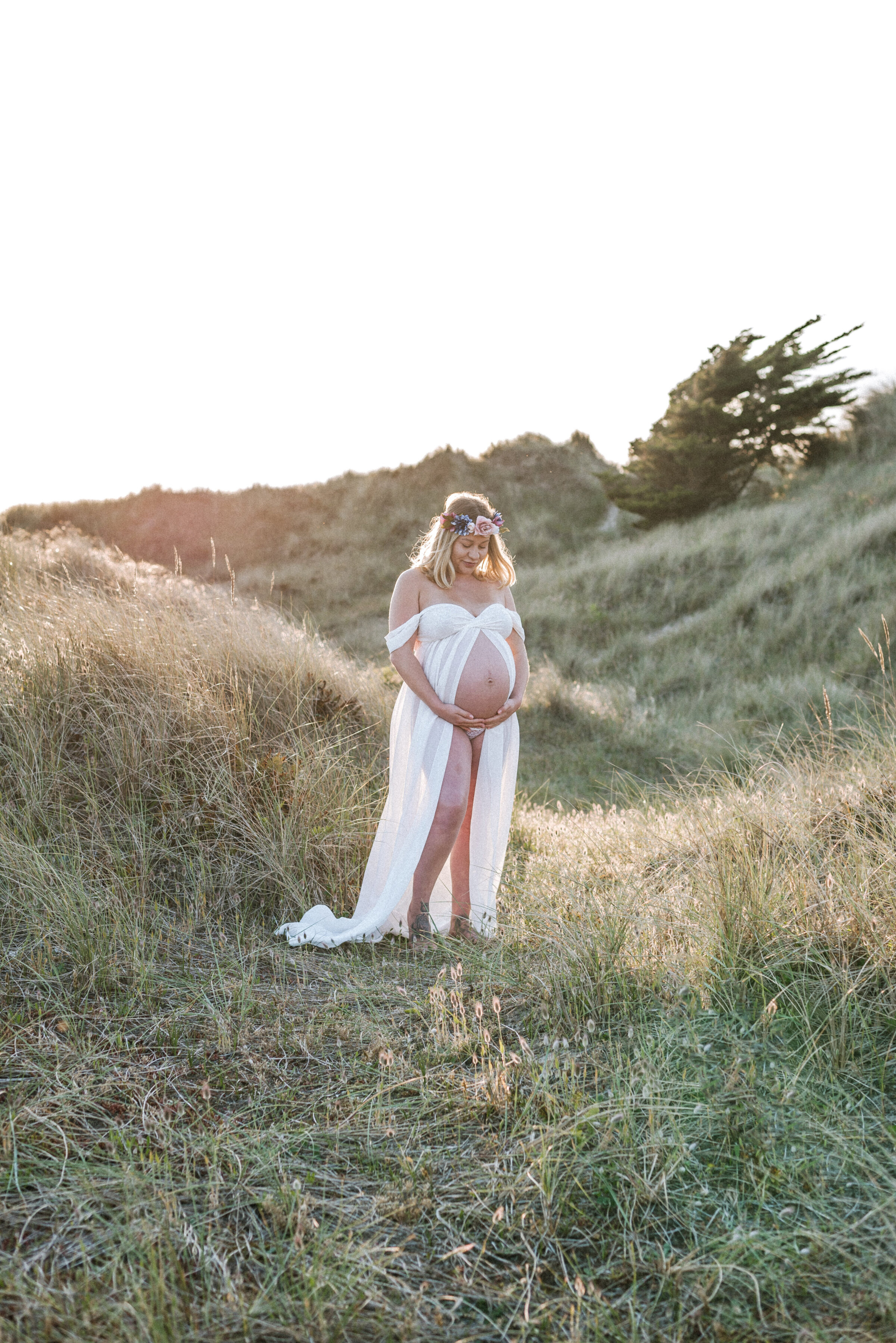 A pregnant women standing in the dunes at the beach at sunset at Billingshurst maternity photoshoot
