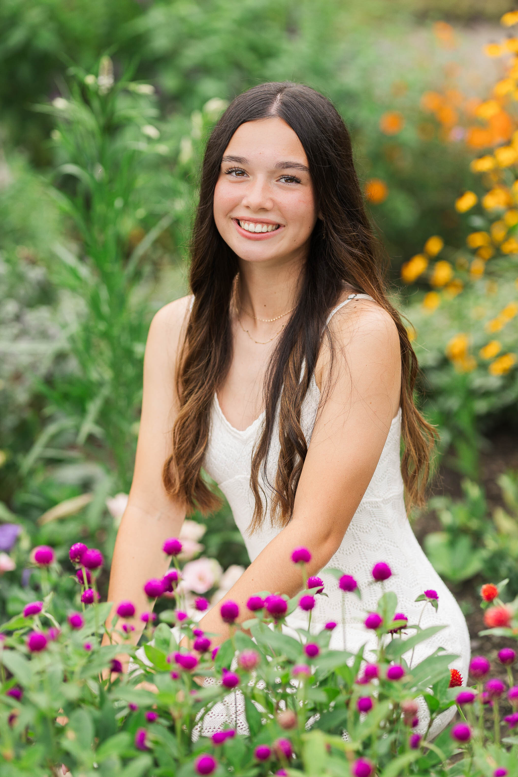 Columbus senior photos at Inniswood Metro Park – a beautiful high school senior sitting by vibrant flowers, captured in natural light for a timeless and elegant portrait