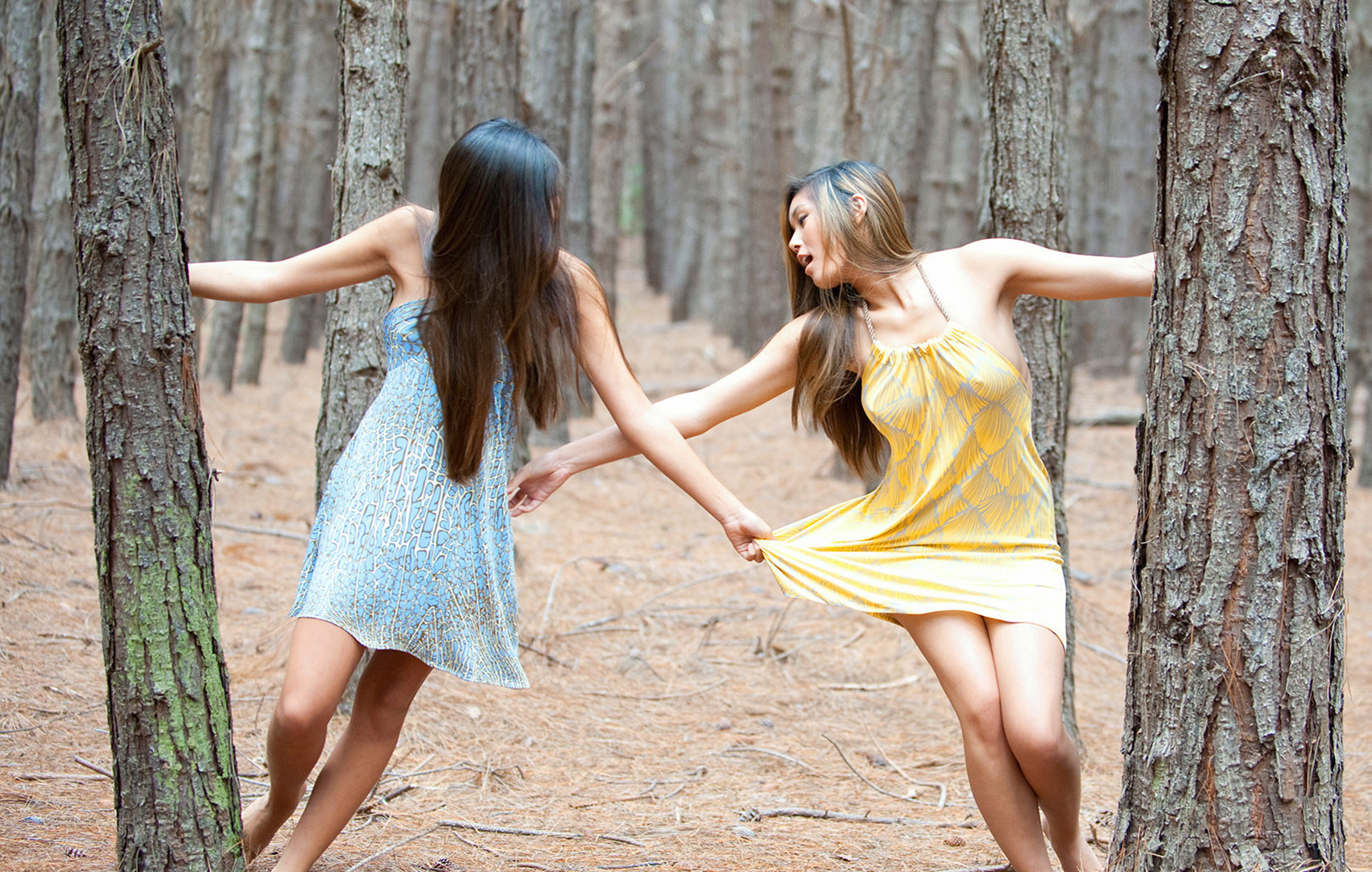 Sisters in the woods play with their dresses.