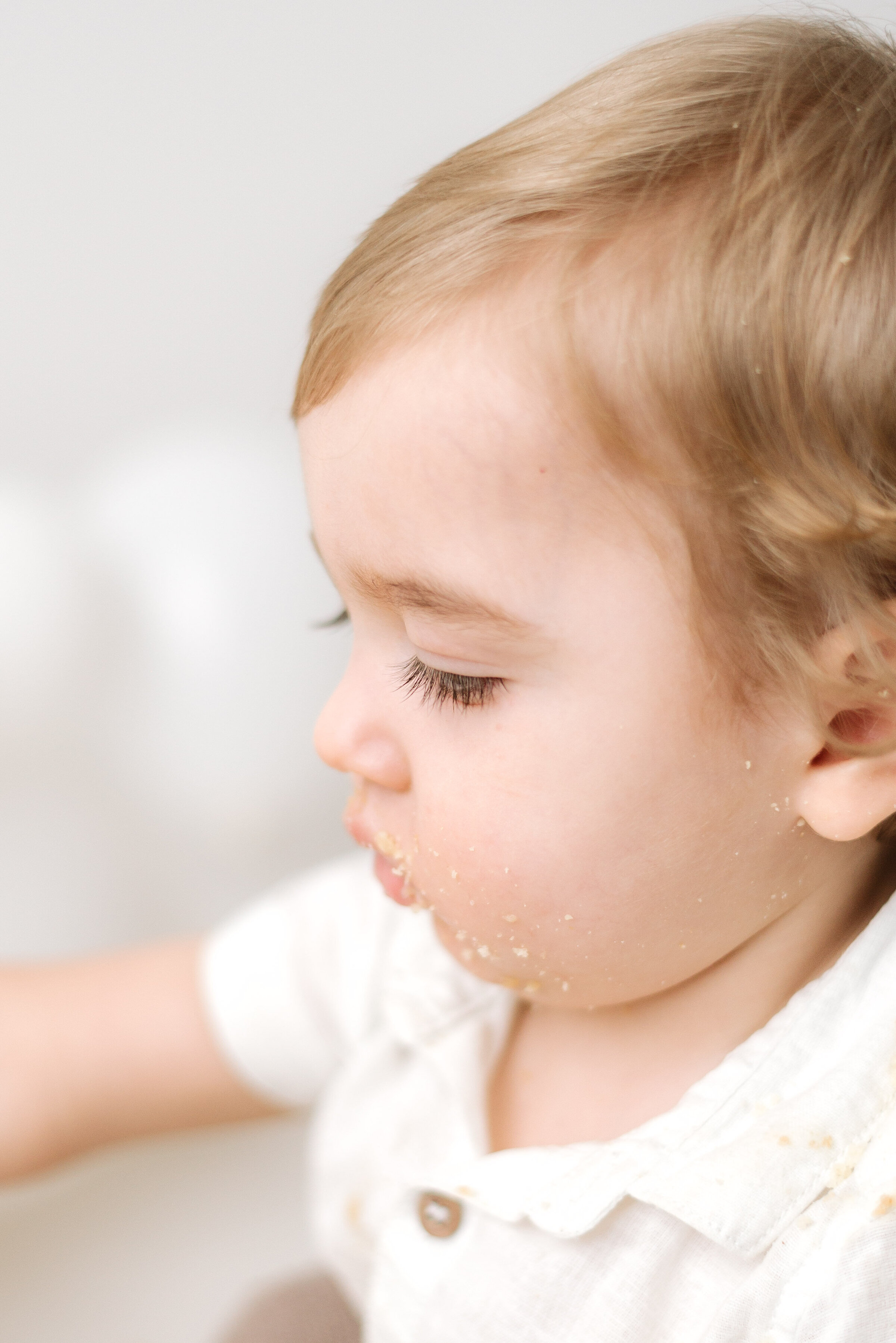 Boy looking down with cake on his face at Billingshurst cake smash photoshoot