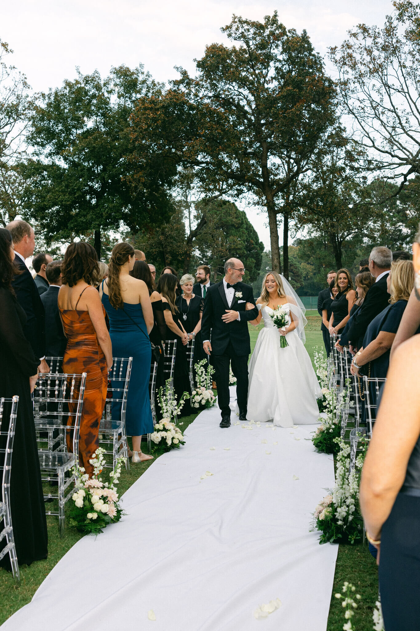 Bride being walked down the aisle by her father during their outdoor ceremony at Texarkana Country Club